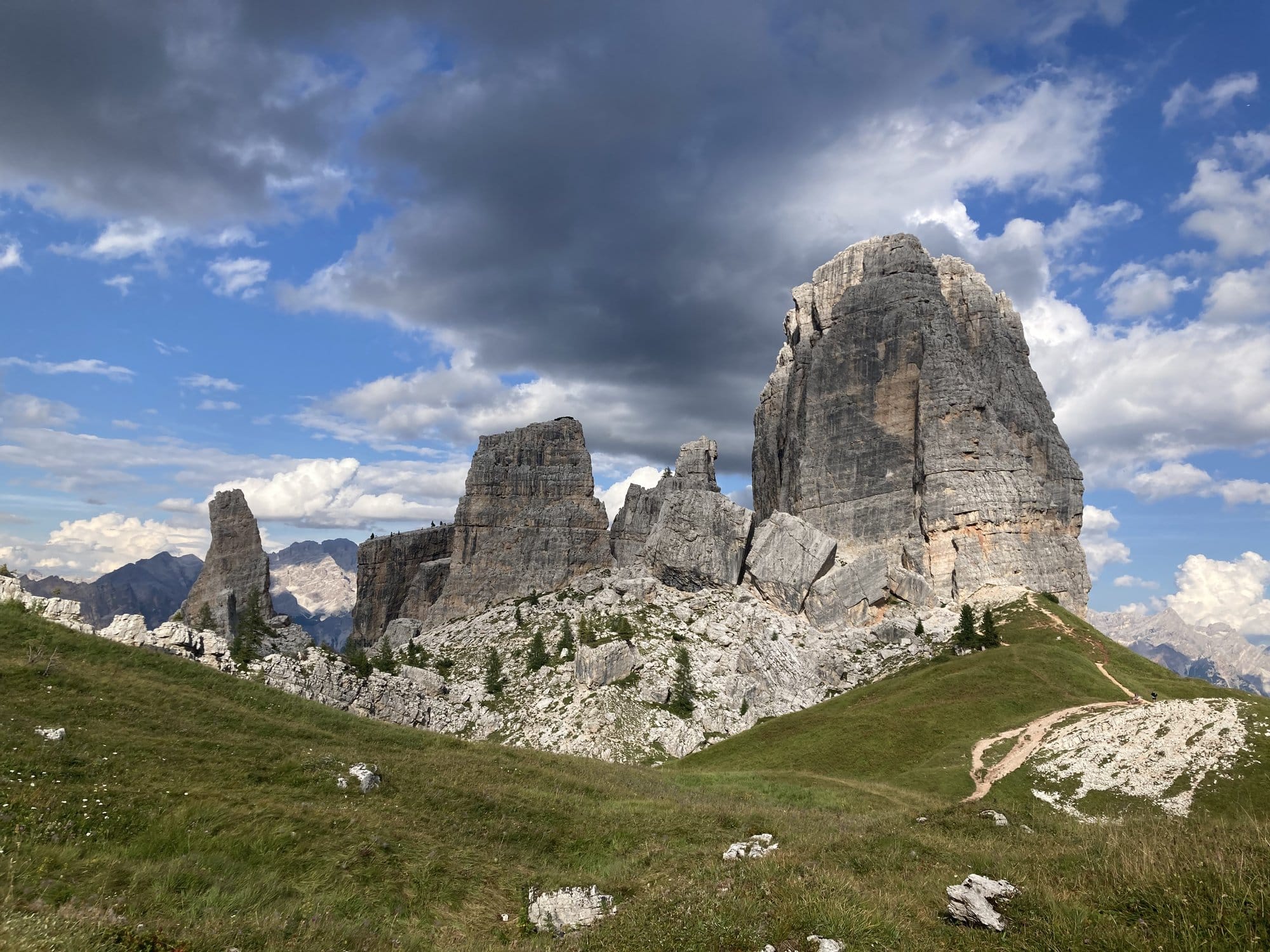 The Cinque Torri rock formations rising from alpine meadows under dramatic skies — Dolomites, Italy