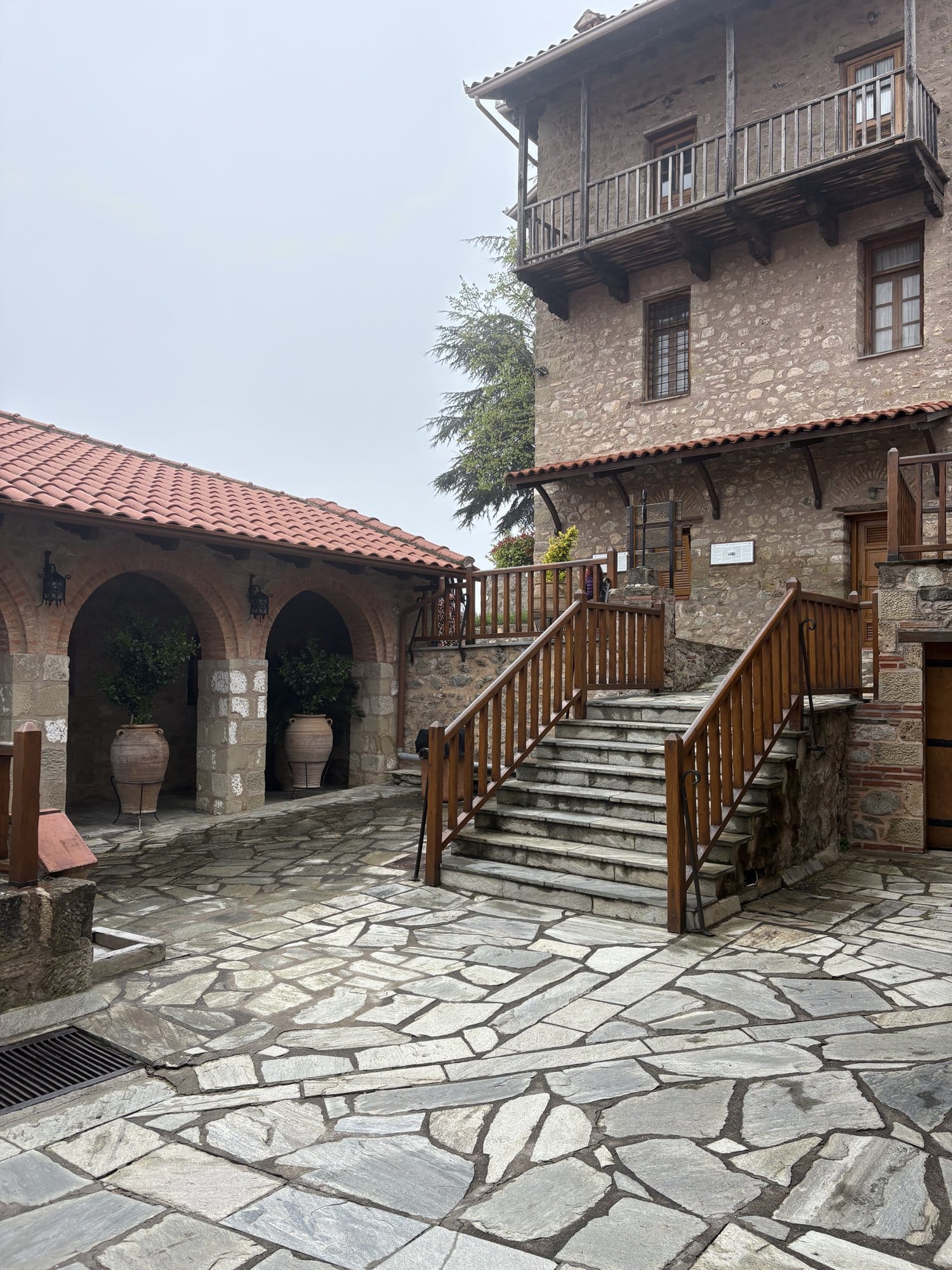 Interior courtyard of a Meteora monastery — stone paving and wooden staircase — Greece