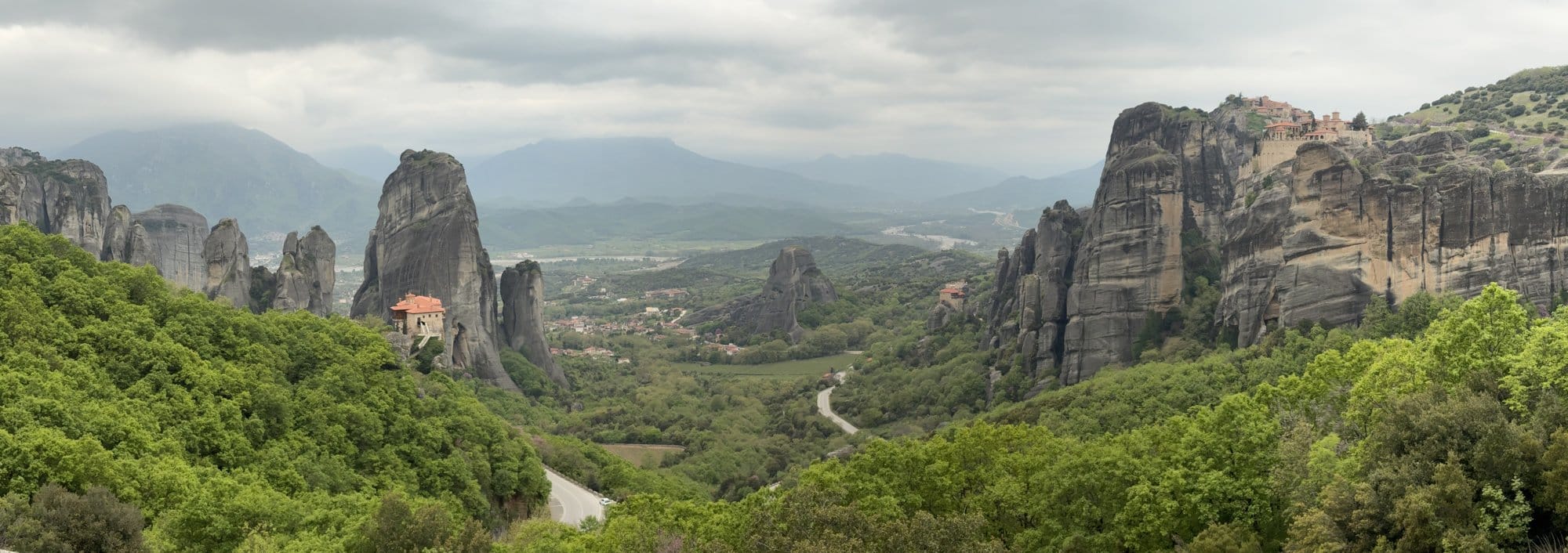 Large panorama des piliers rocheux de Meteora et de la vallée sous un ciel nuageux — Grèce