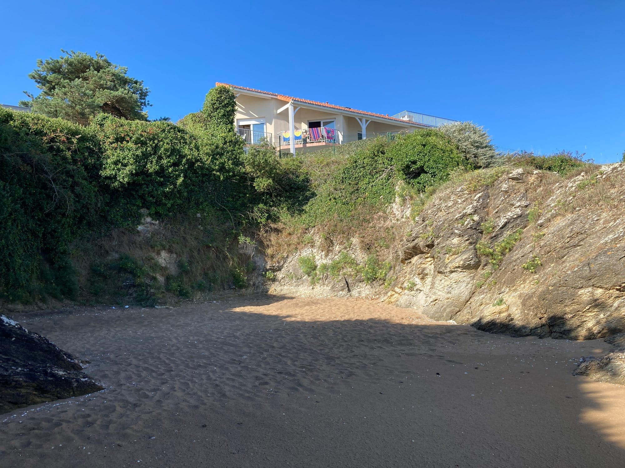 Small secluded cove nestled between limestone cliffs with a house on the rocky headland