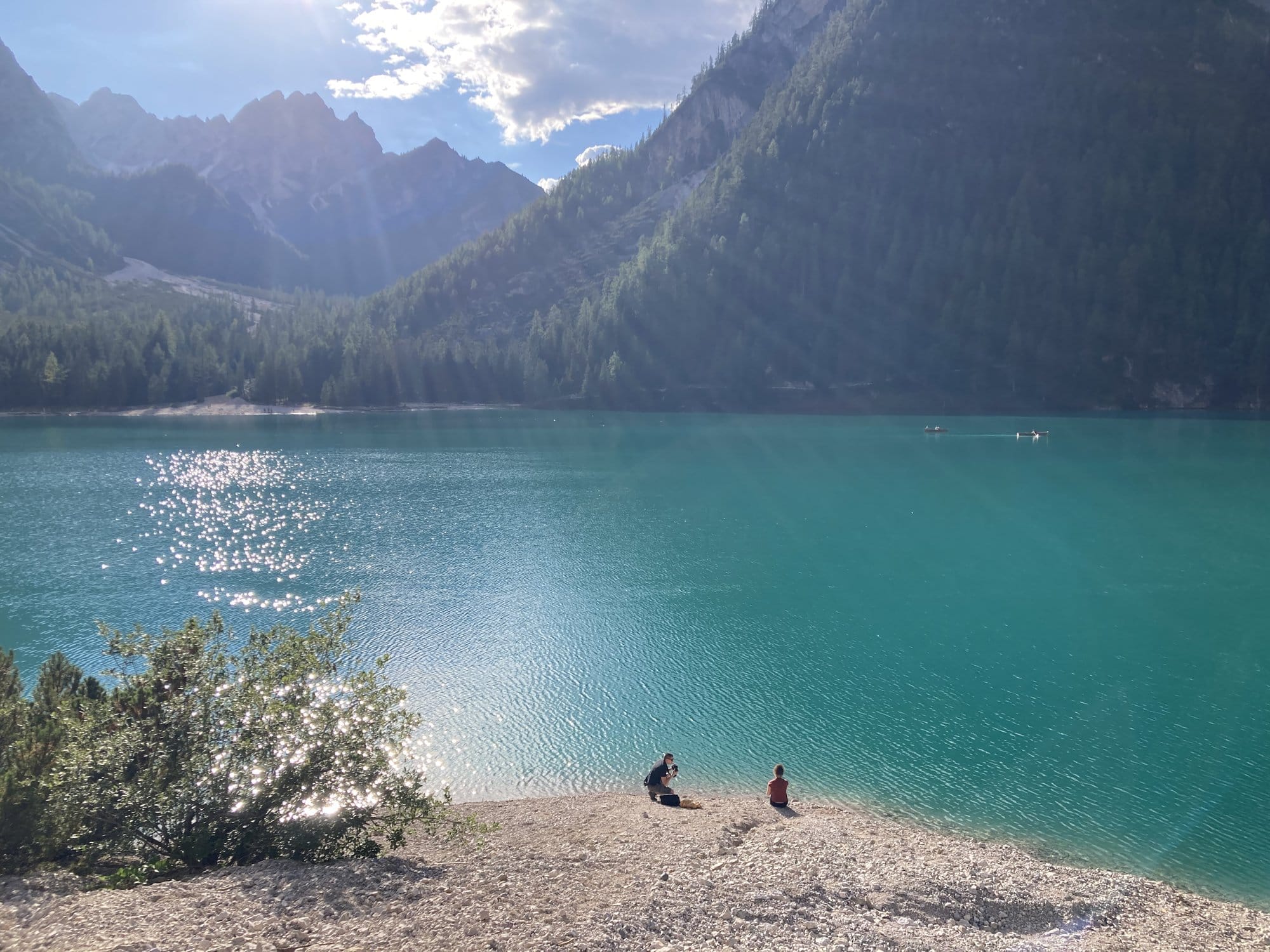 The rocky shore of Lago di Braies with turquoise water and forested mountains โ Dolomites, Italy