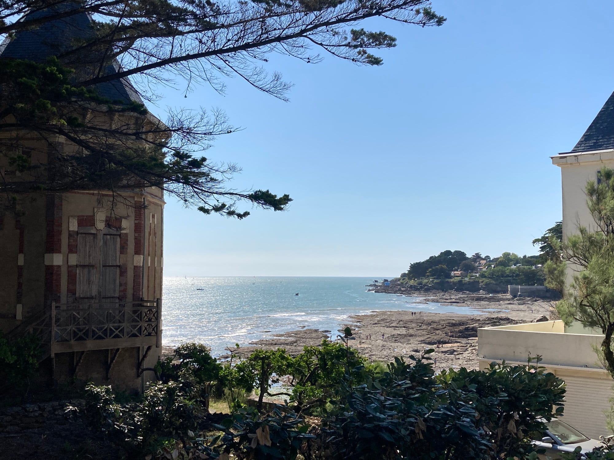 Charming old Belle Époque villa glimpsed between stone towers with a small rocky beach visible below