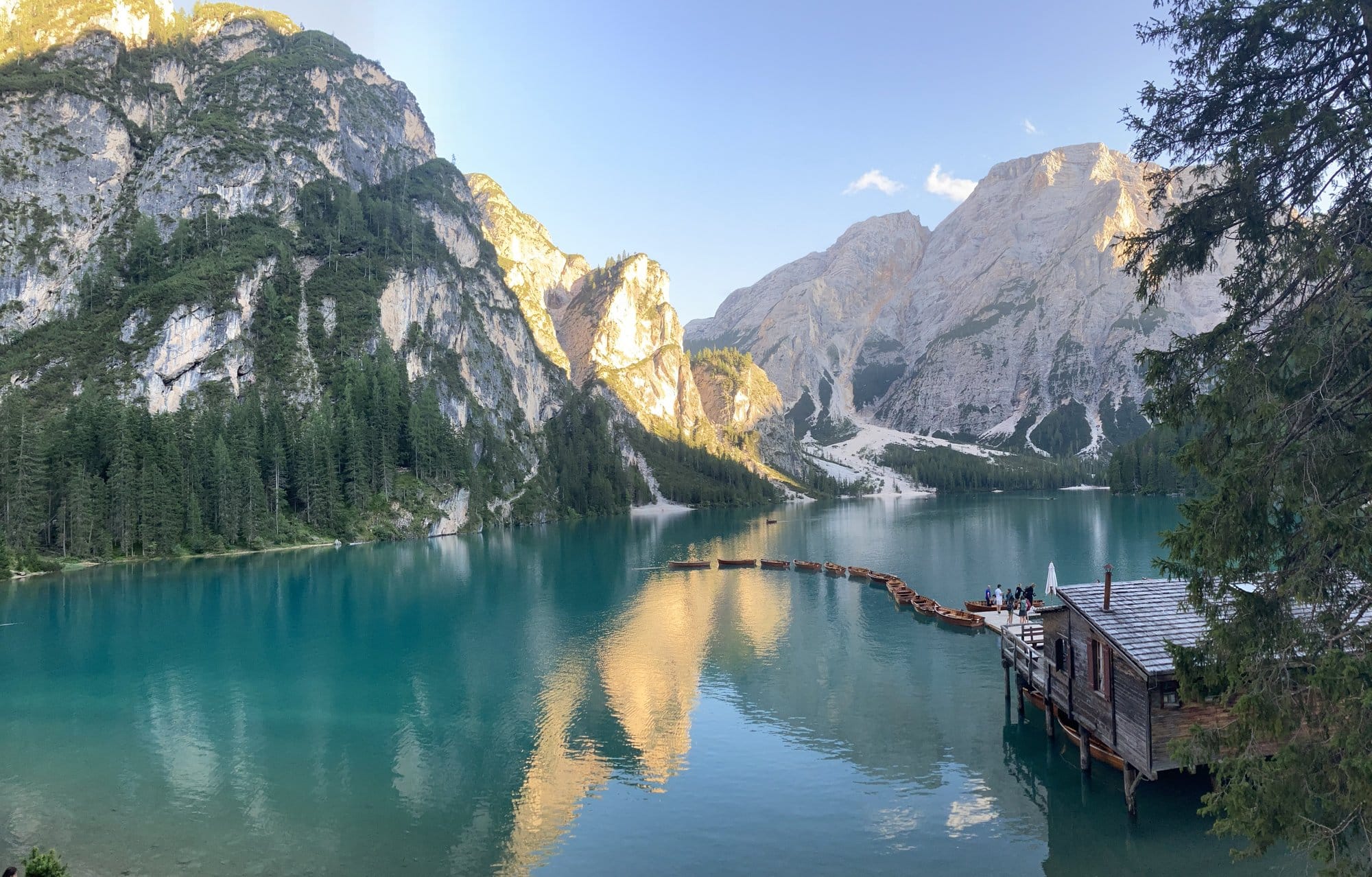 The iconic wooden boathouse at Lago di Braies with turquoise water and mountain backdrop โ Dolomites, Italy