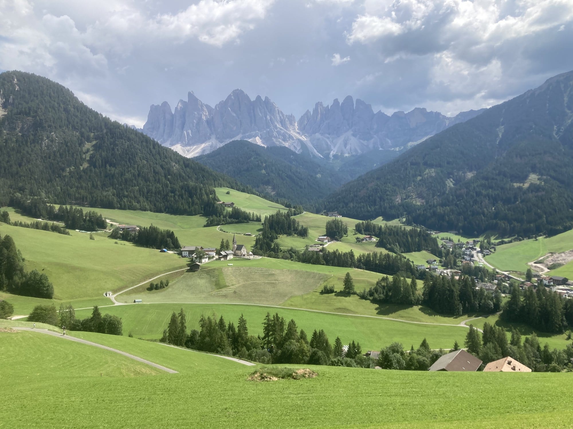 Val di Funes village with conifer forests and the Odle massif in the background โ Dolomites, Italy