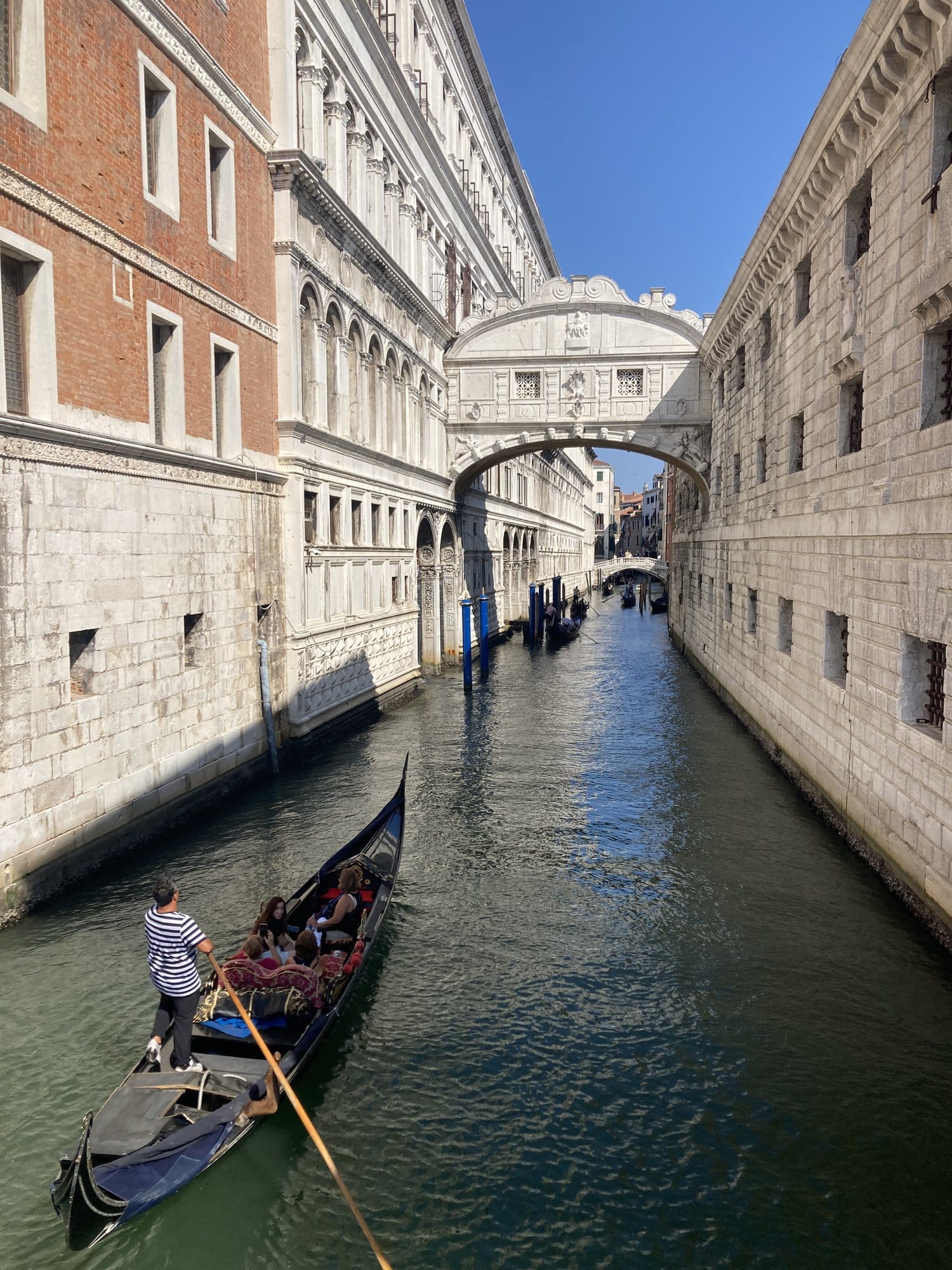 The Bridge of Sighs with a gondola passing through the narrow canal — Venice, Italy