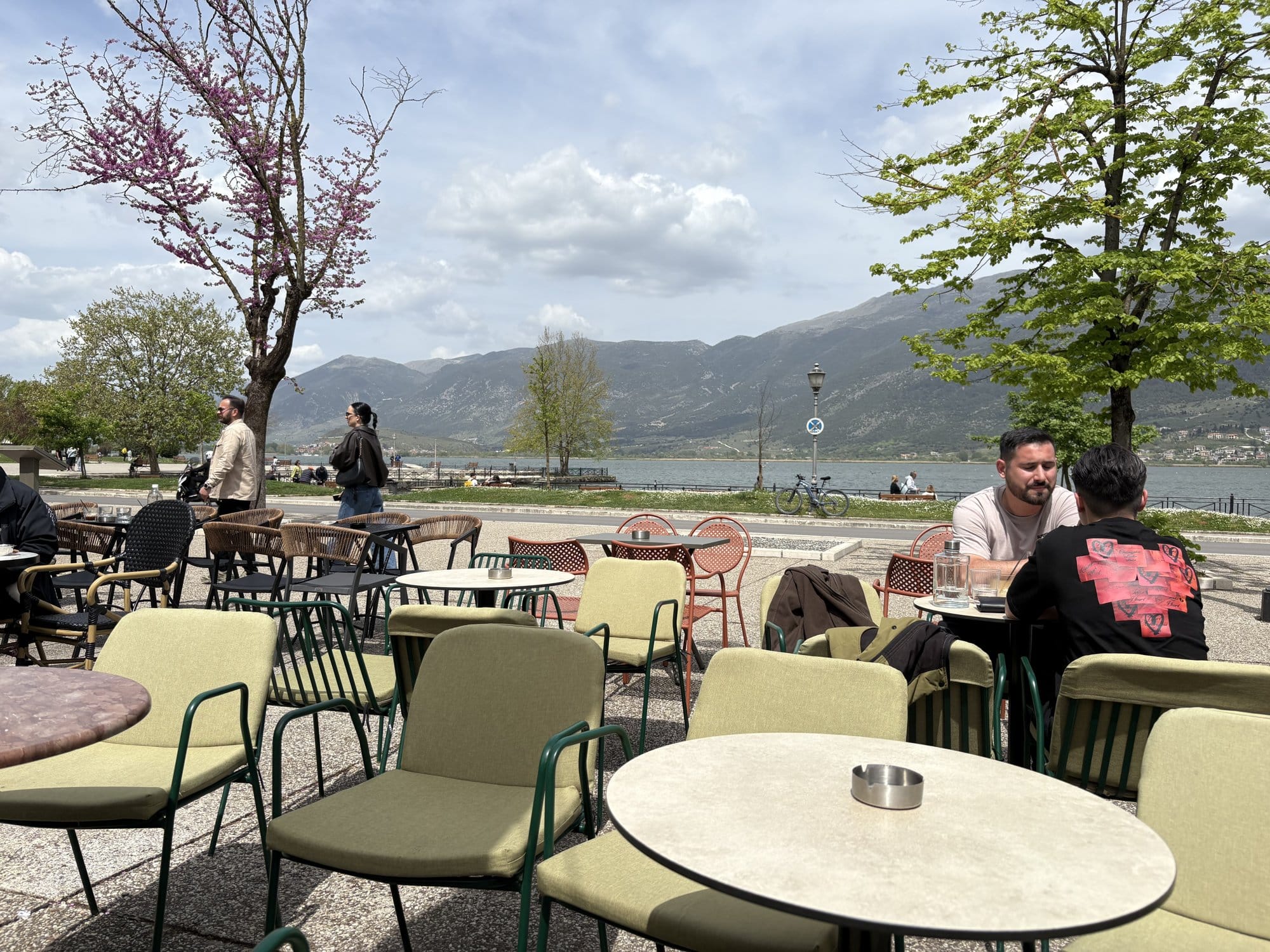 Ioannina lakefront café terrace with tables under blossoming trees — Greece
