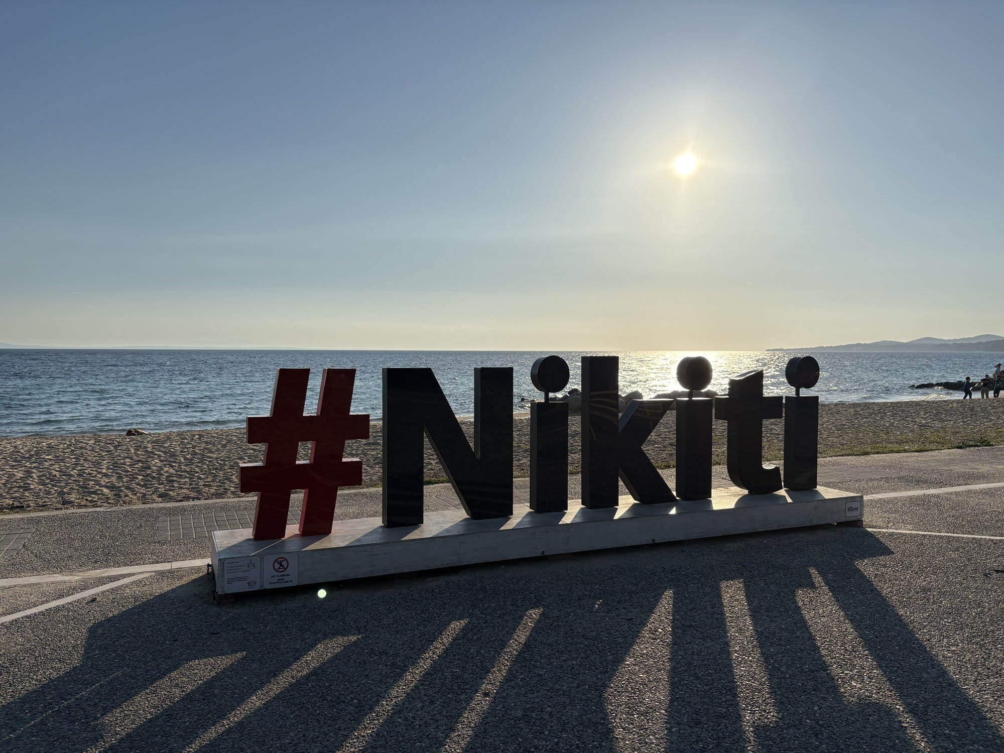 Grand panneau #Nikiti sur le front de mer avec la plage et le coucher de soleil derrière — Halkidiki, Grèce
