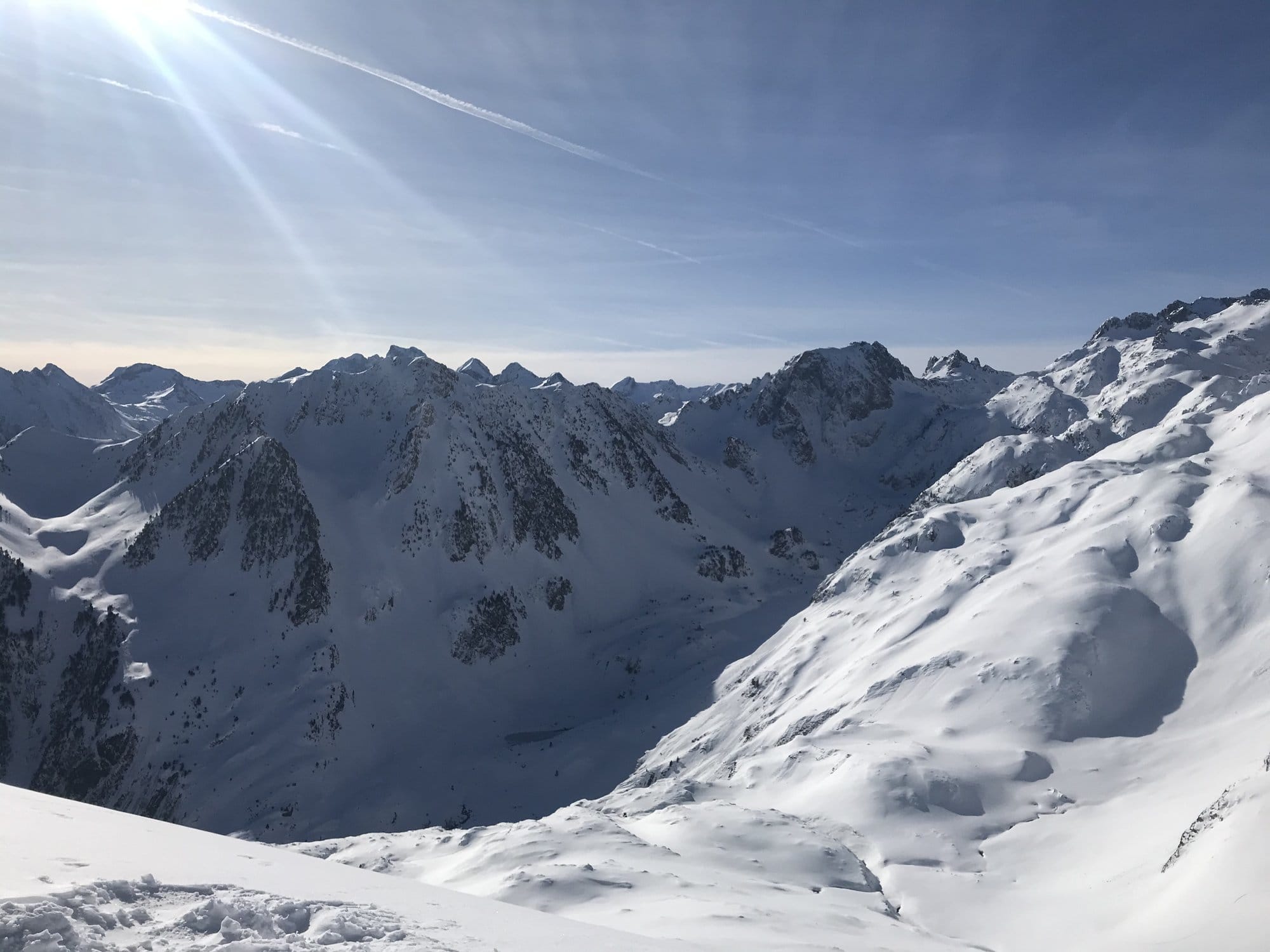 Panoramic view from the summit of the Cirque du Lys — the Pyrenean peaks stretching into the distance under a brilliant blue sky and blazing sun — Cauterets, France