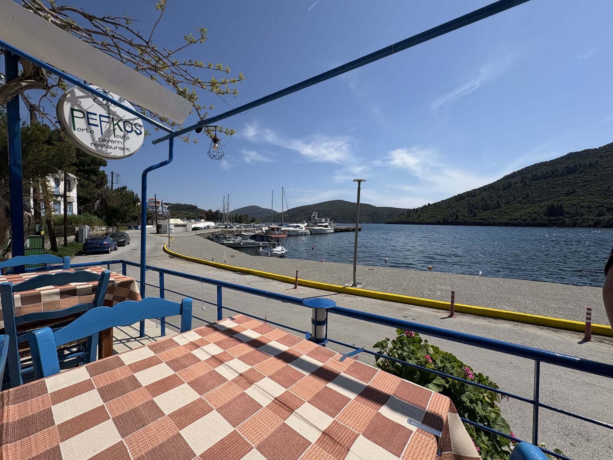 Terrasse de taverna à Porto Koufo avec nappes à carreaux rouges et vue sur le port — Sithonia, Grèce