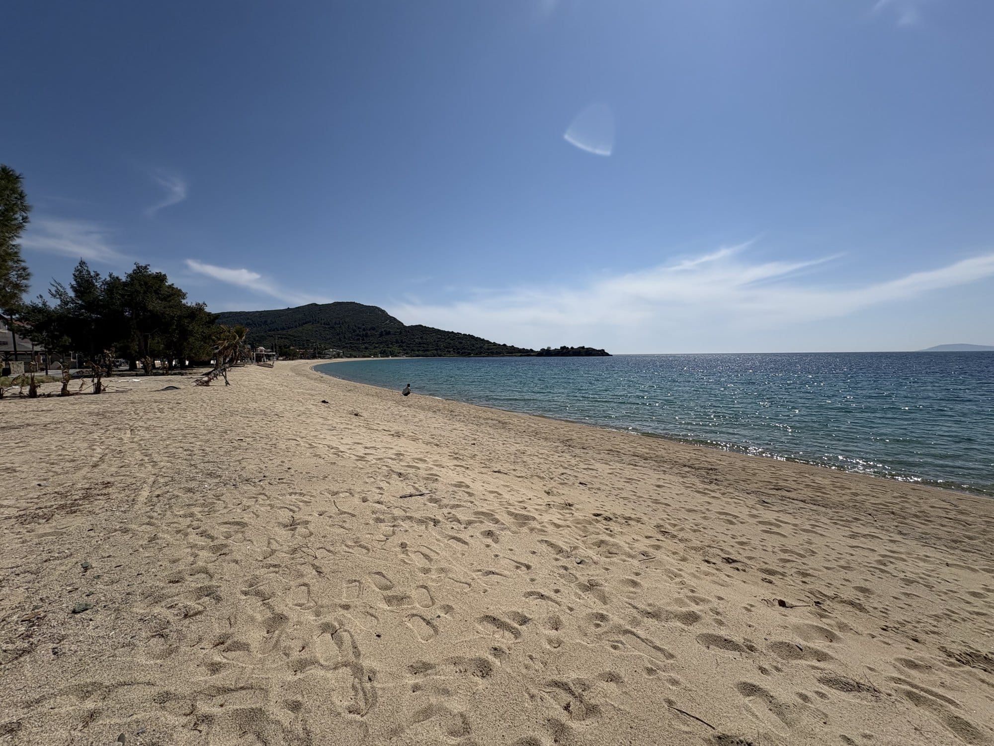 Grande plage sableuse déserte avec mer bleue et collines derrière — Sithonia, Grèce