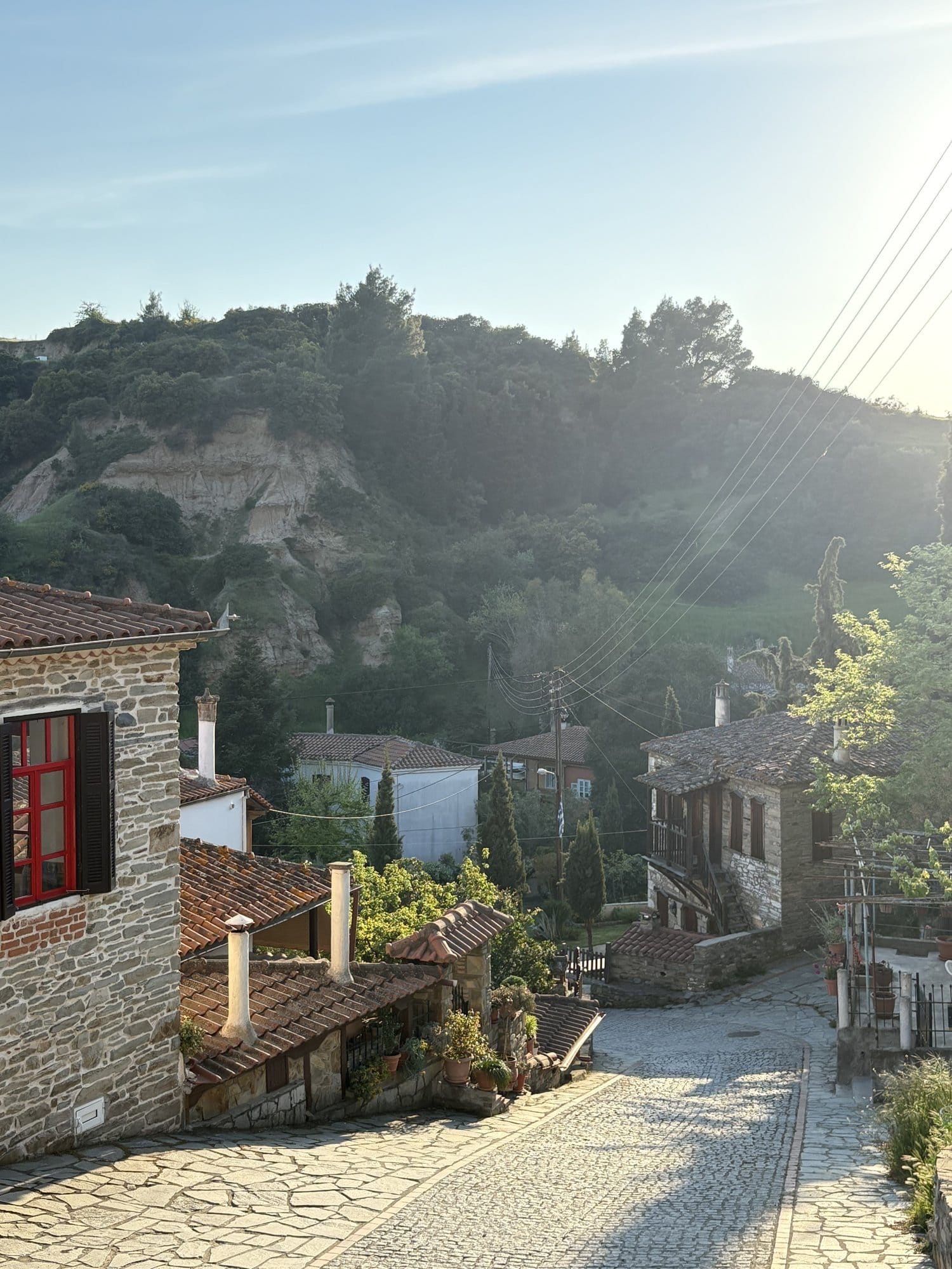 Ruelle pavée de Parthenonas au crépuscule avec maisons en pierre et soleil doré — Grèce