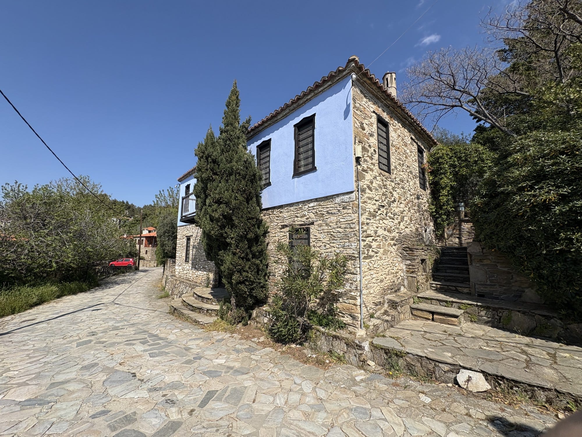 Maison en pierre peinte en bleu le long d'une ruelle pavée à Parthenonas — Sithonia, Grèce