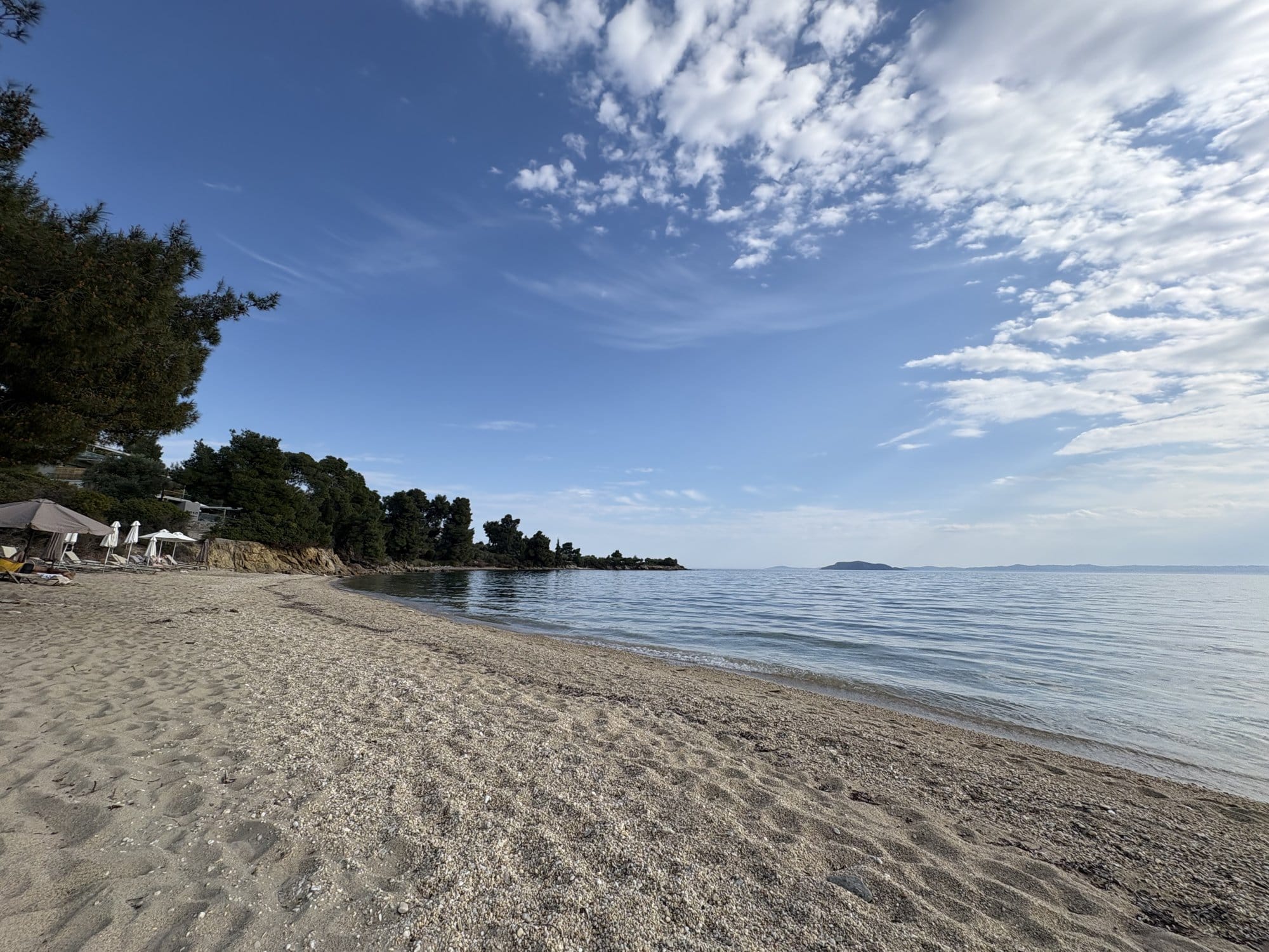 Plage de Sithonia avec mer calme, pins et ciel nuageux — Grèce