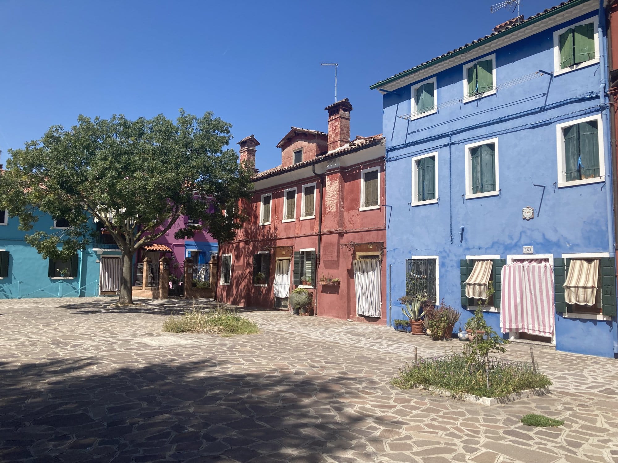 Colorful houses lining a square in Burano — Venice, Italy
