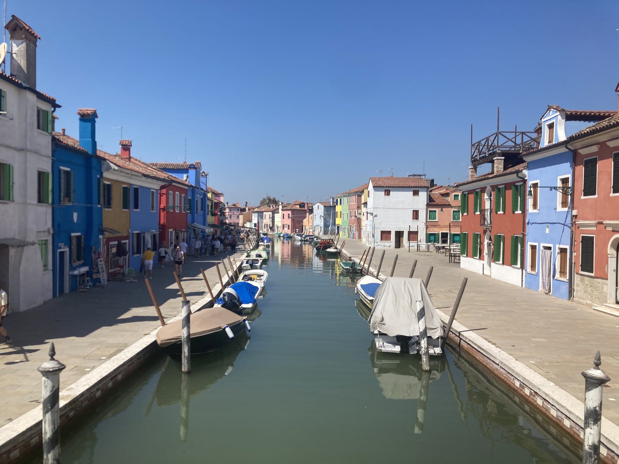 Burano's main canal lined with multicolored houses and moored boats — Venice, Italy