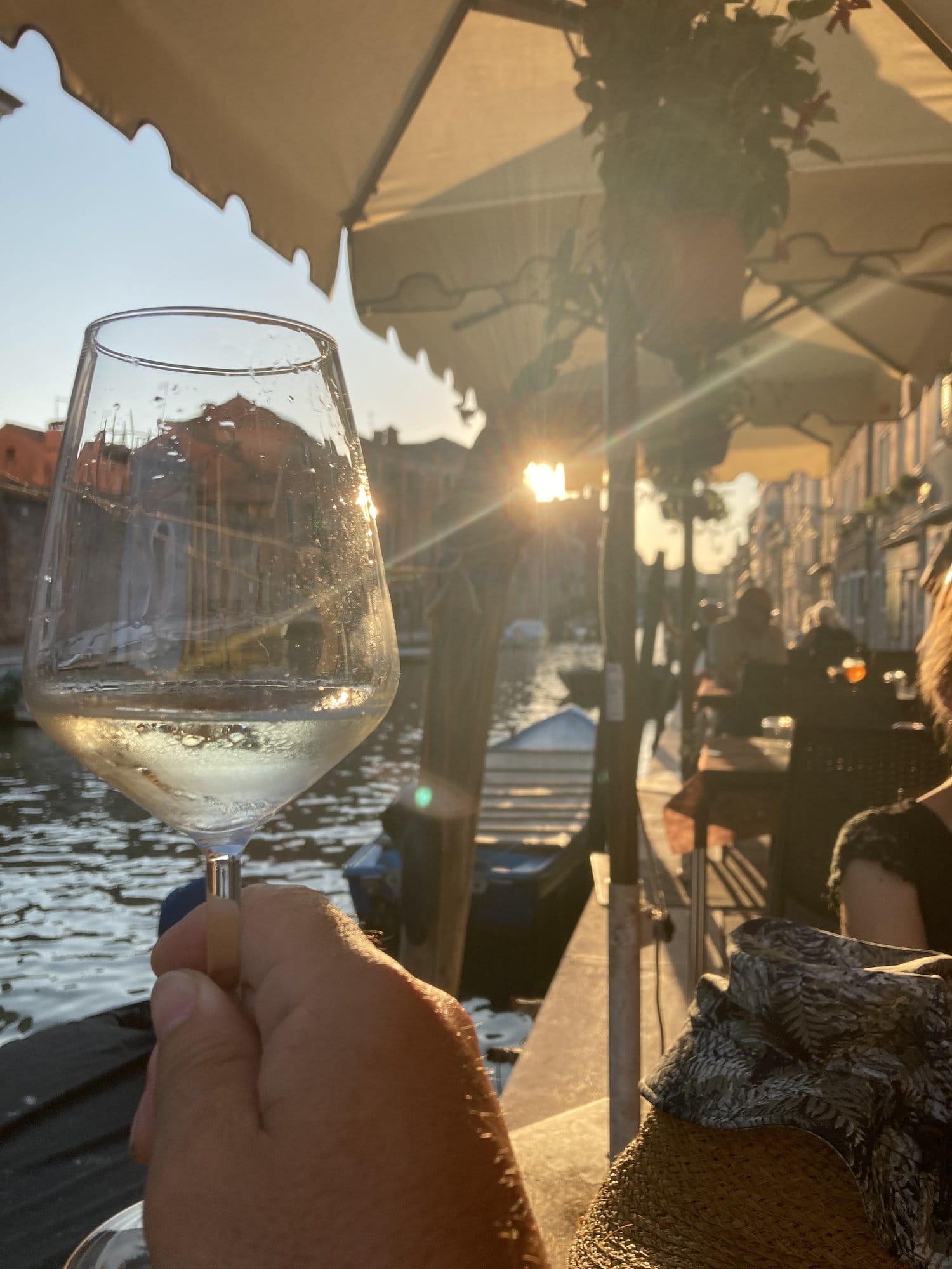 Glass of white wine with sunset reflections on the Cannaregio canal — Venice, Italy