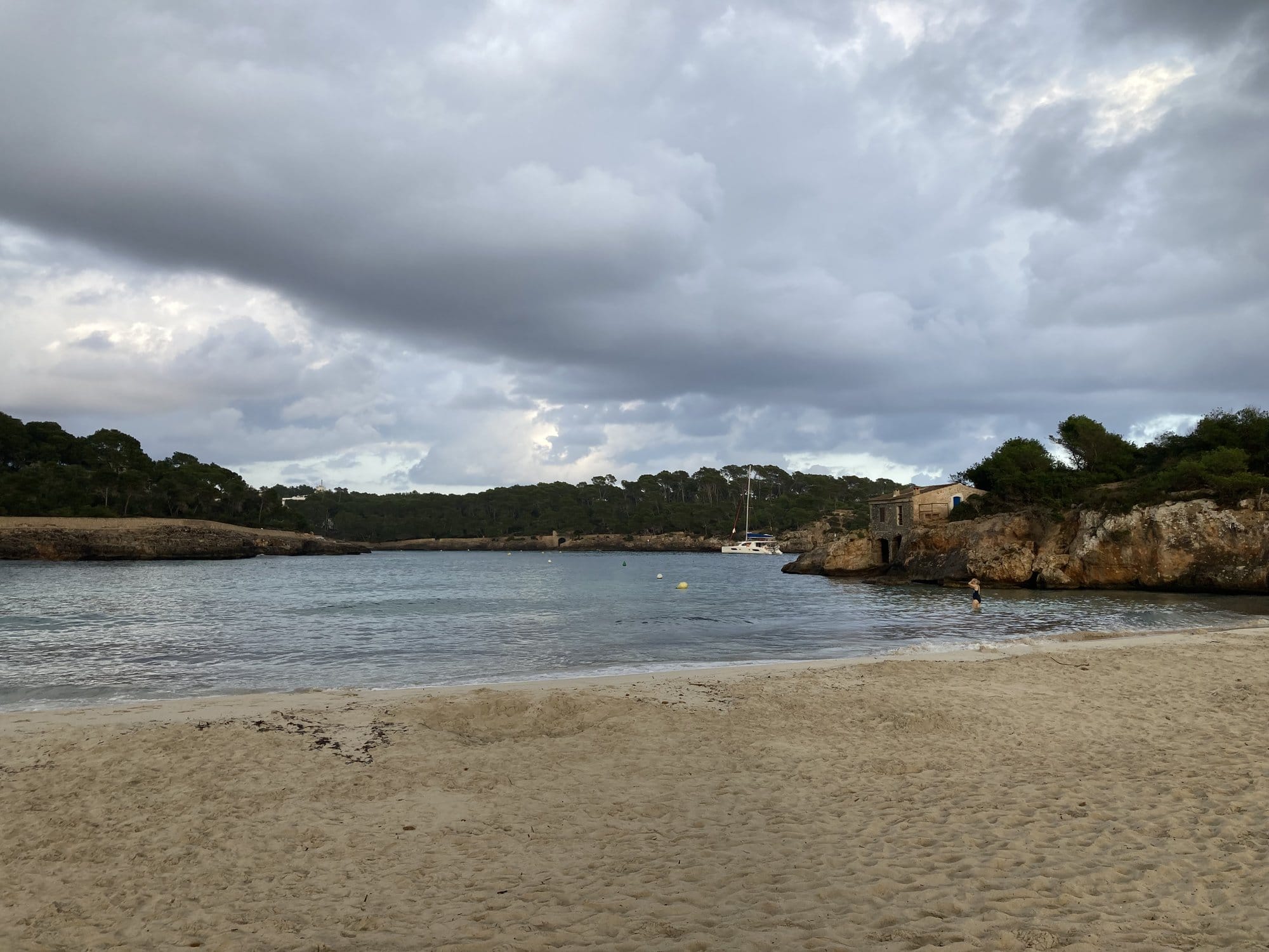 Sandy beach in a turquoise cove sheltered by limestone cliffs — Santanyí Bay, Spain