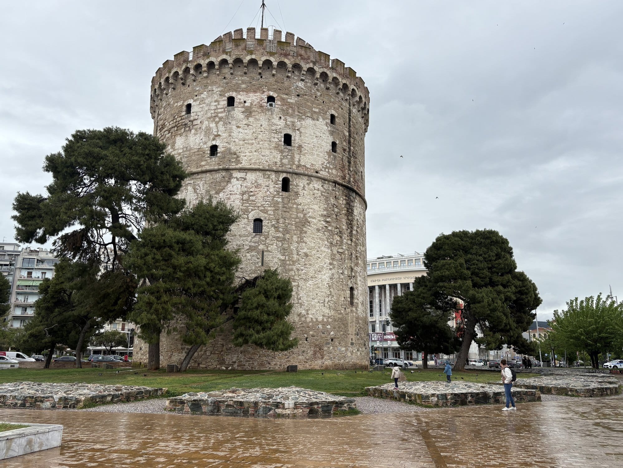 La Tour Blanche de Thessalonique sous un ciel nuageux, avec des murs en ruines à sa base — Grèce
