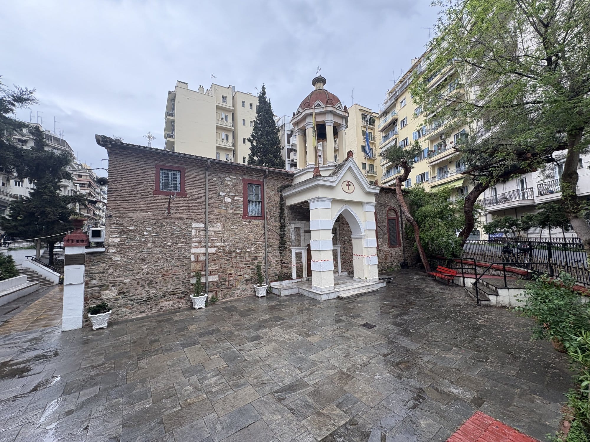 Petite chapelle byzantine en pierre avec clocher à tuiles rouges sur une place mouillée à Thessalonique — Grèce