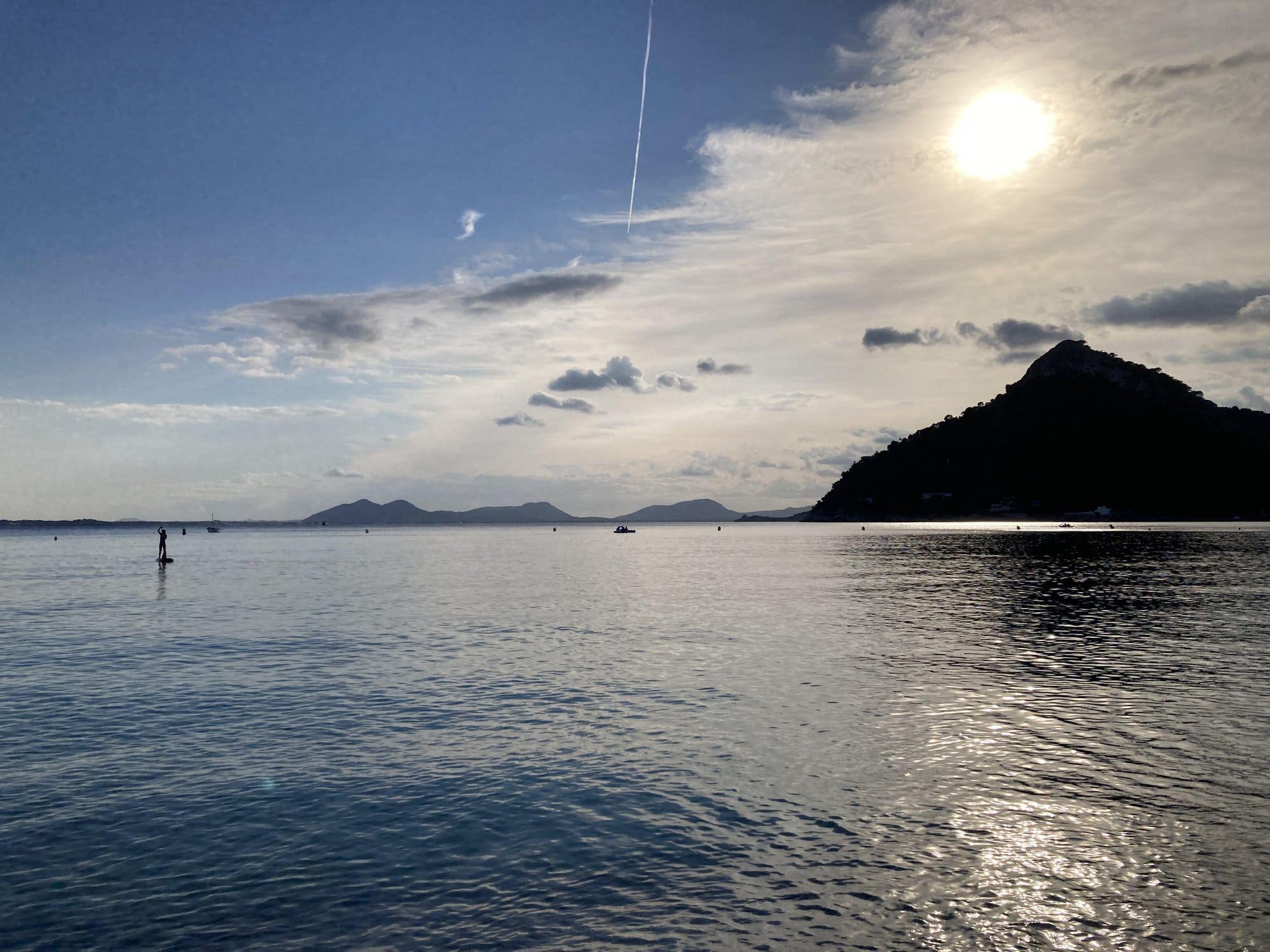Sunset view across the bay with a sailboat anchored offshore — Pollença, Spain