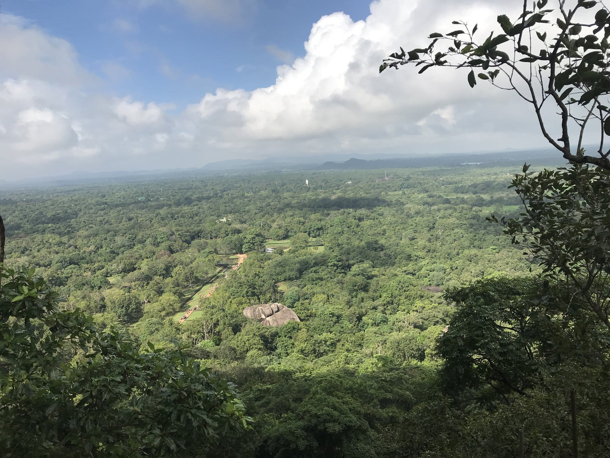 Panoramic view from Sigiriya's summit overlooking forested valleys, distant rock formations rising above mist, the landscape stretching to the horizon — Sigiriya, Sri Lanka