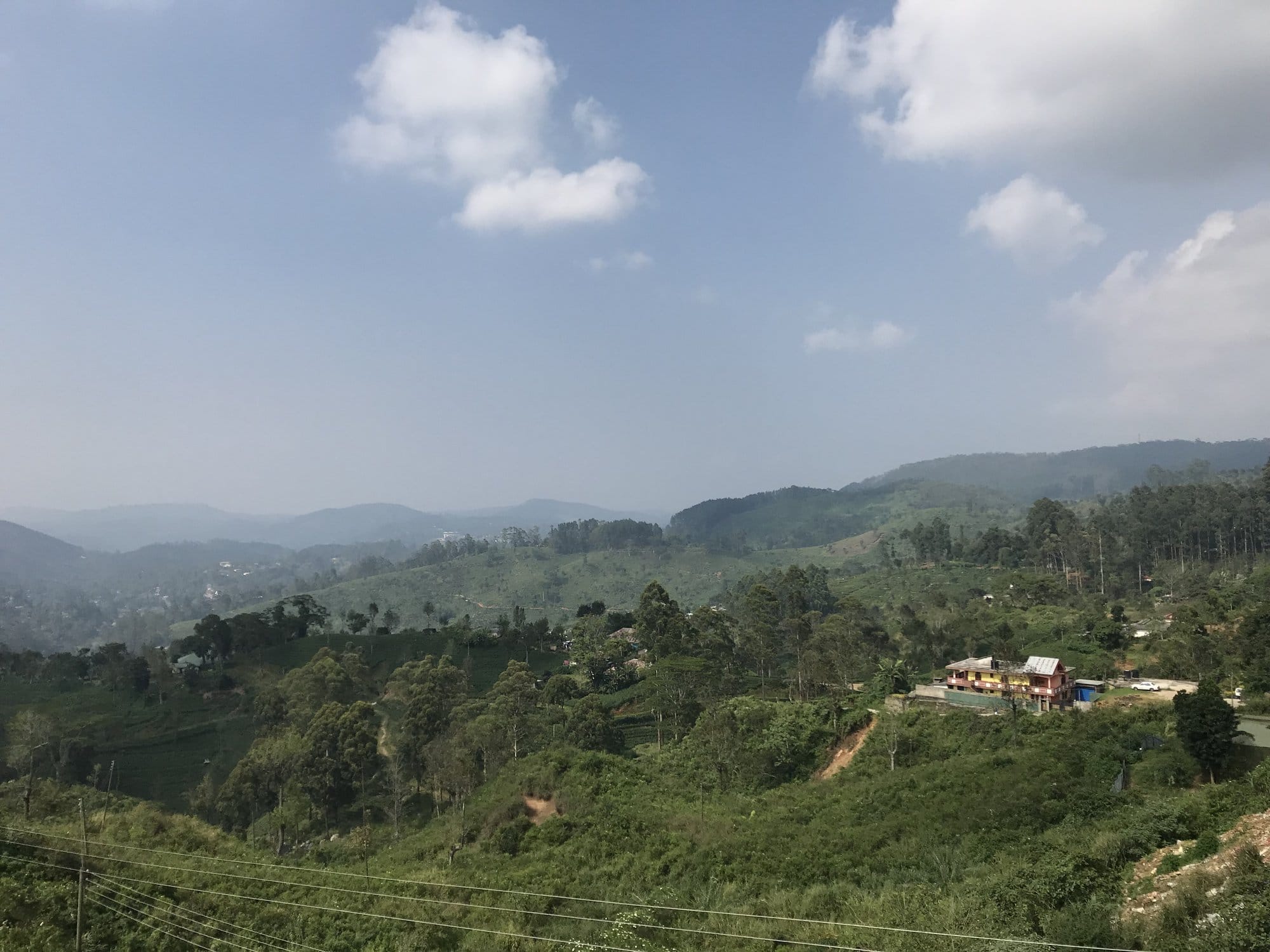 Vast panorama of tea-covered hills and scattered settlements viewed from the highlands — Horton Plains, Sri Lanka