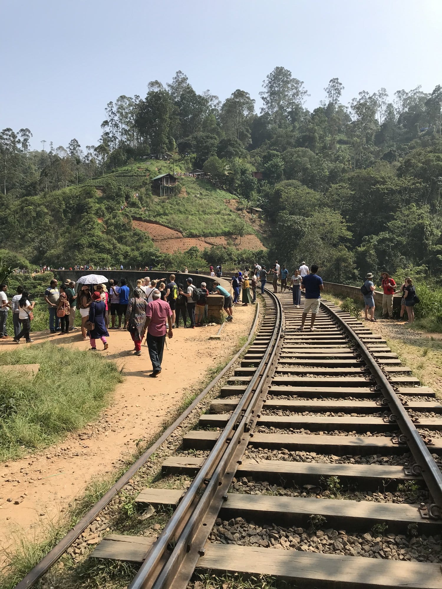 Historic railway tracks with local crowd gathered alongside at a small highland station — Ella, Sri Lanka