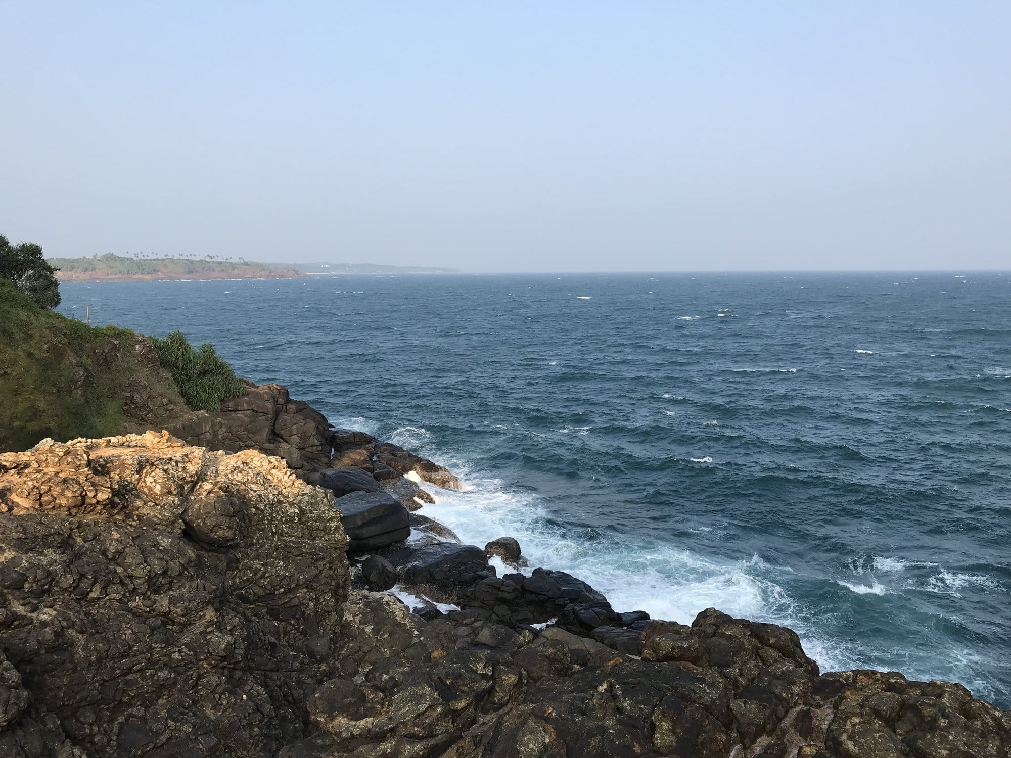 Rocky coastal headland with dark granite boulders and churning Indian Ocean swell — Tangalle, Sri Lanka