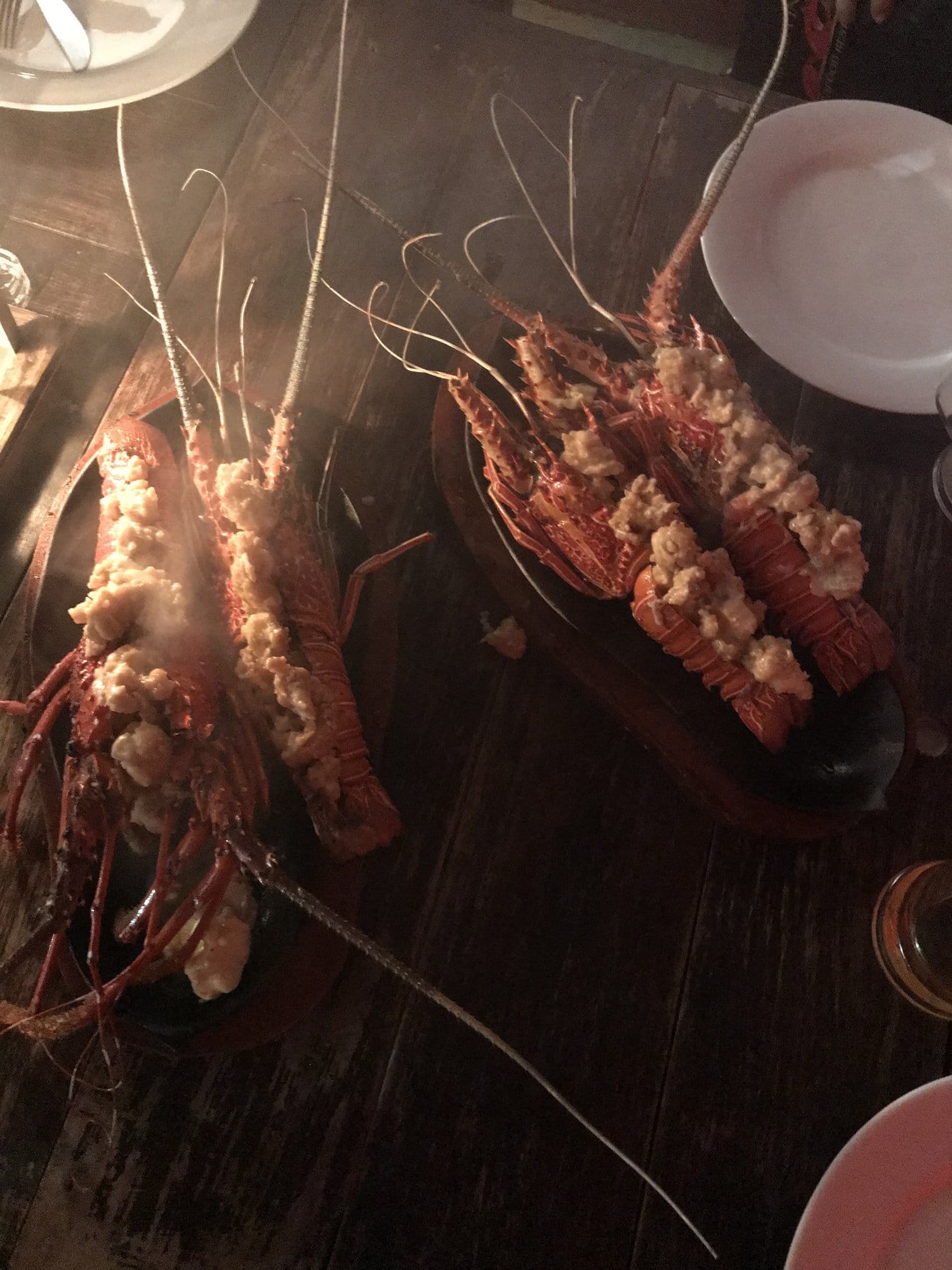 Beach at golden hour with swimmers silhouetted against warm light and rocky outcrops offshore — Mirissa, Sri Lanka