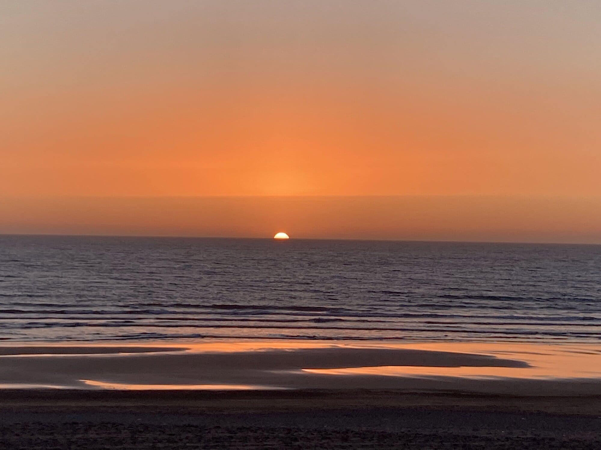 A caravan of camels crosses the beach at Smimou in silhouette against the setting sun — Smimou, Morocco