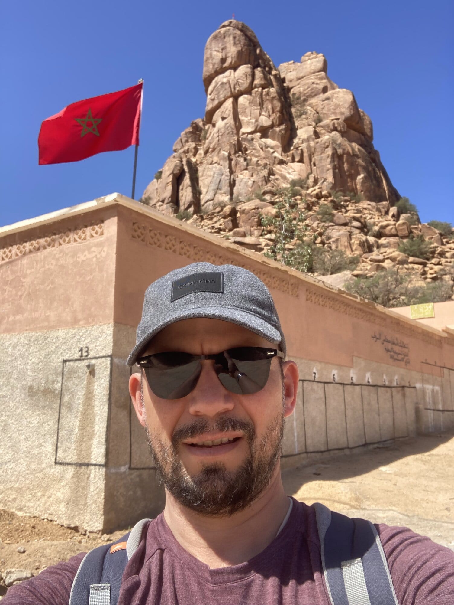 The Chapeau de Napoléon formation above Tafraout, with the Moroccan flag flying beside the famous granite boulder — Tafraout, Morocco