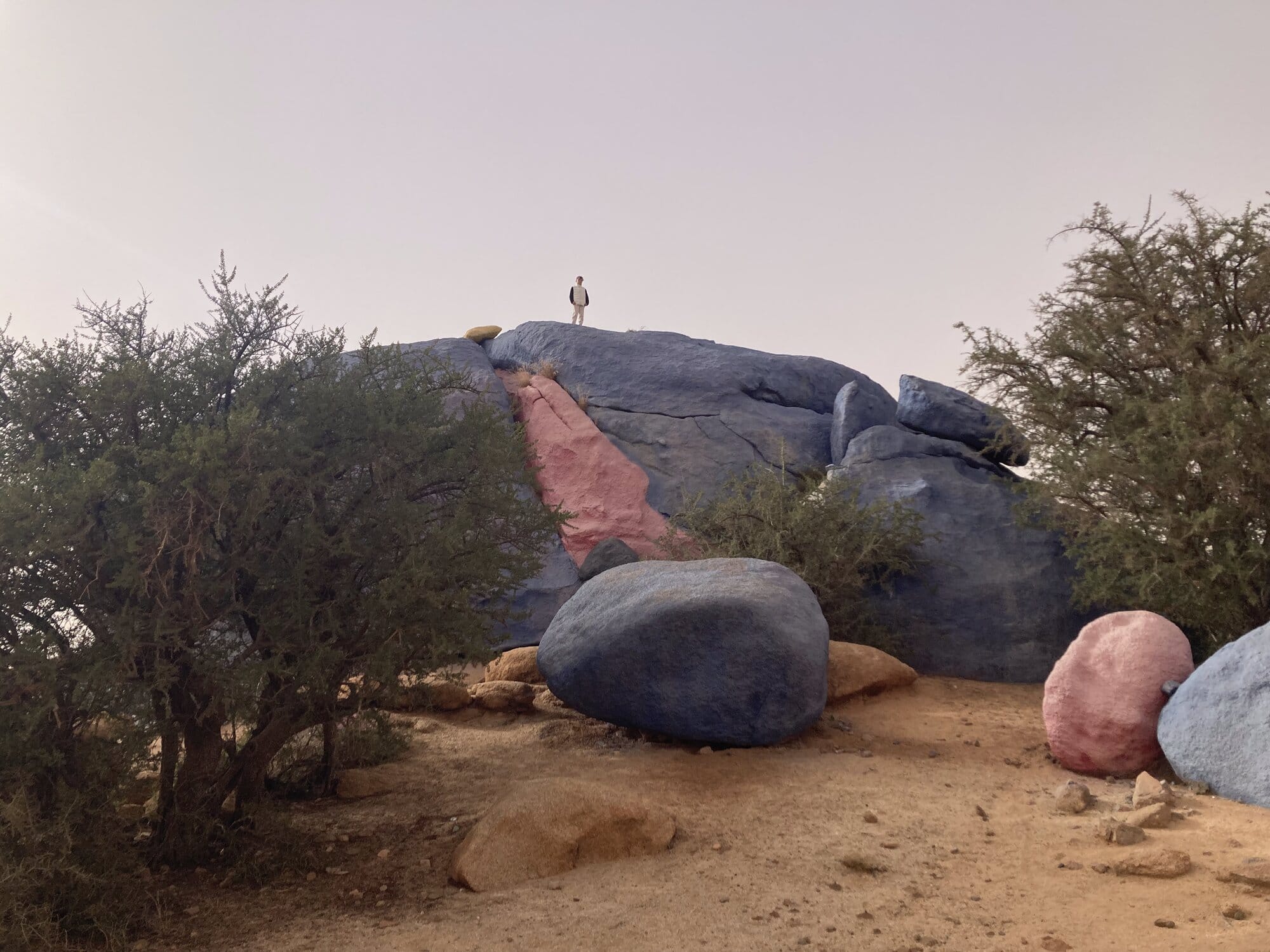 A close-up of one of the Painted Rocks with a figure standing on top for scale — near Tafraout, Morocco