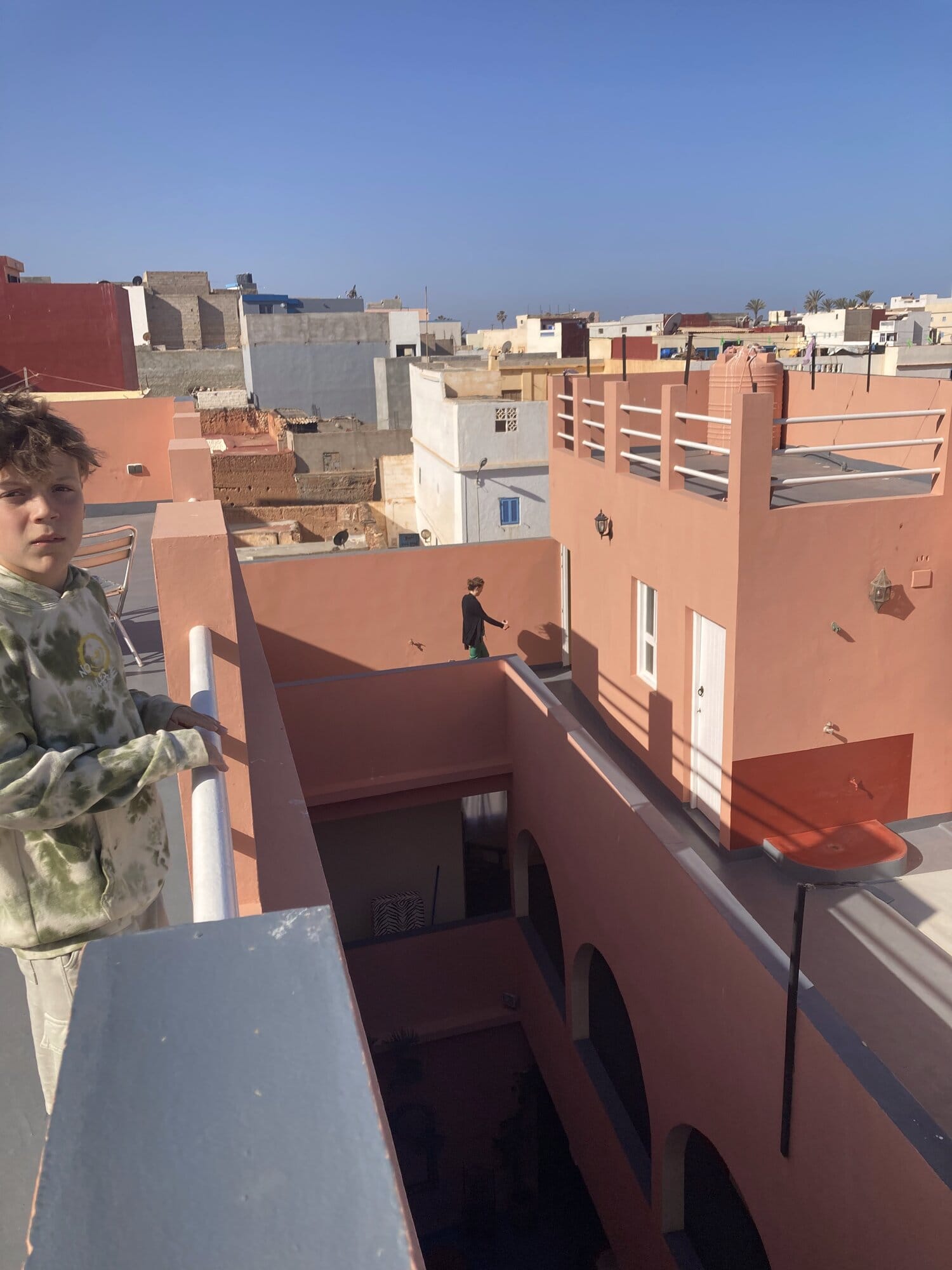 Rooftop panorama of Sidi Ifni at dusk — pastel art-deco buildings and a white minaret against the Atlantic — Sidi Ifni, Morocco