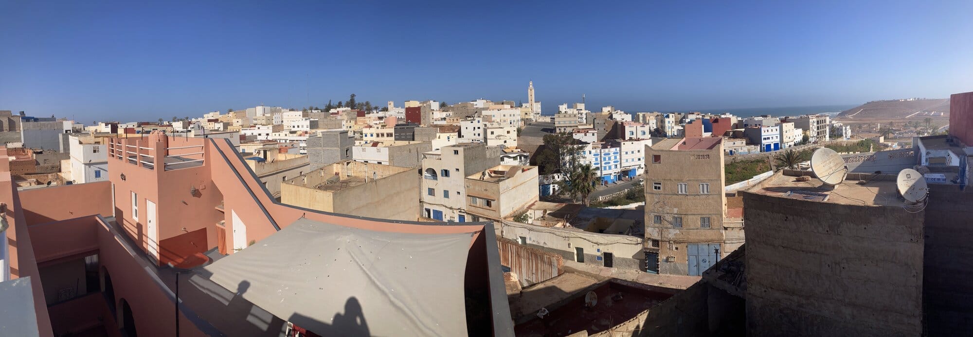 A second rooftop angle of Sidi Ifni at dusk with cleaner sight-lines to the minaret and the sea beyond — Sidi Ifni, Morocco