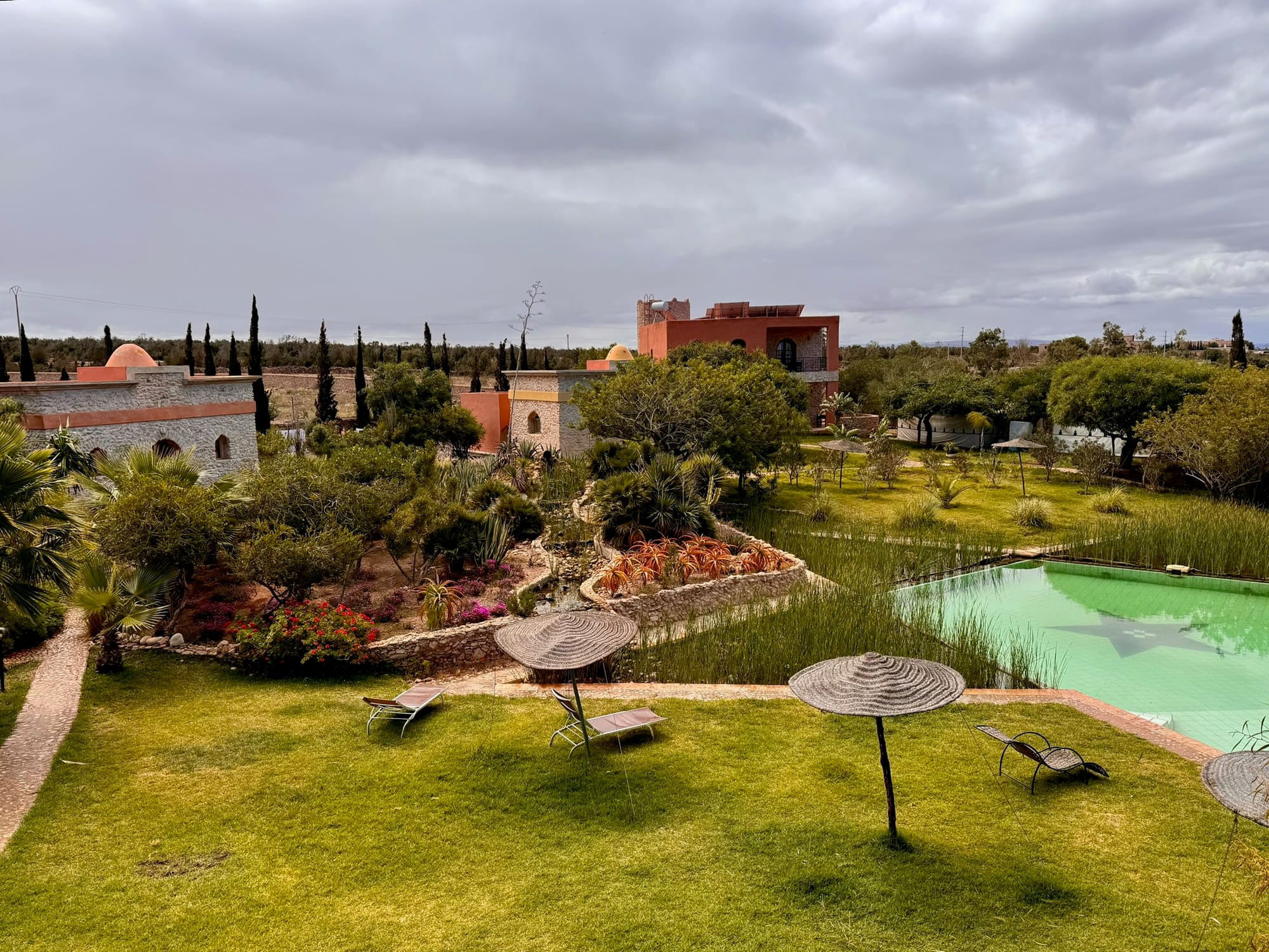 The rose-ochre kasbah buildings and infinity pool at Douar Noujoum, the yoga retreat inland from Essaouira — Ounagha, Morocco