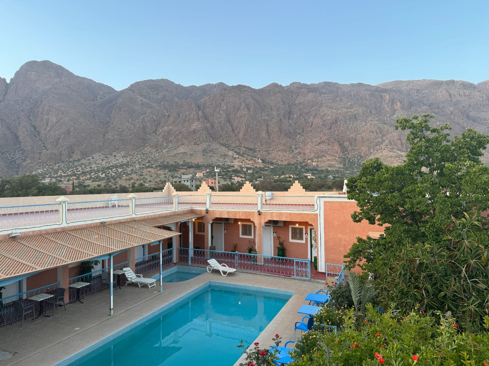 A Tafraout hotel with pool in the foreground and the Anti-Atlas mountains turning gold at sunset behind — Tafraout, Morocco