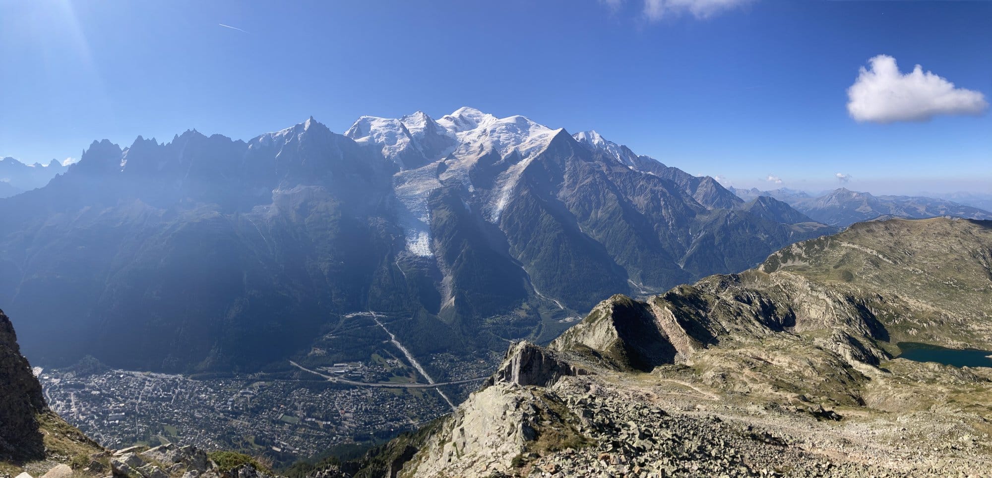 Panoramic view from Le Brévent summit at 2,488m showing the full Mont-Blanc massif, the valley of Chamonix far below, and an alpine lake — Chamonix-Mont-Blanc, France