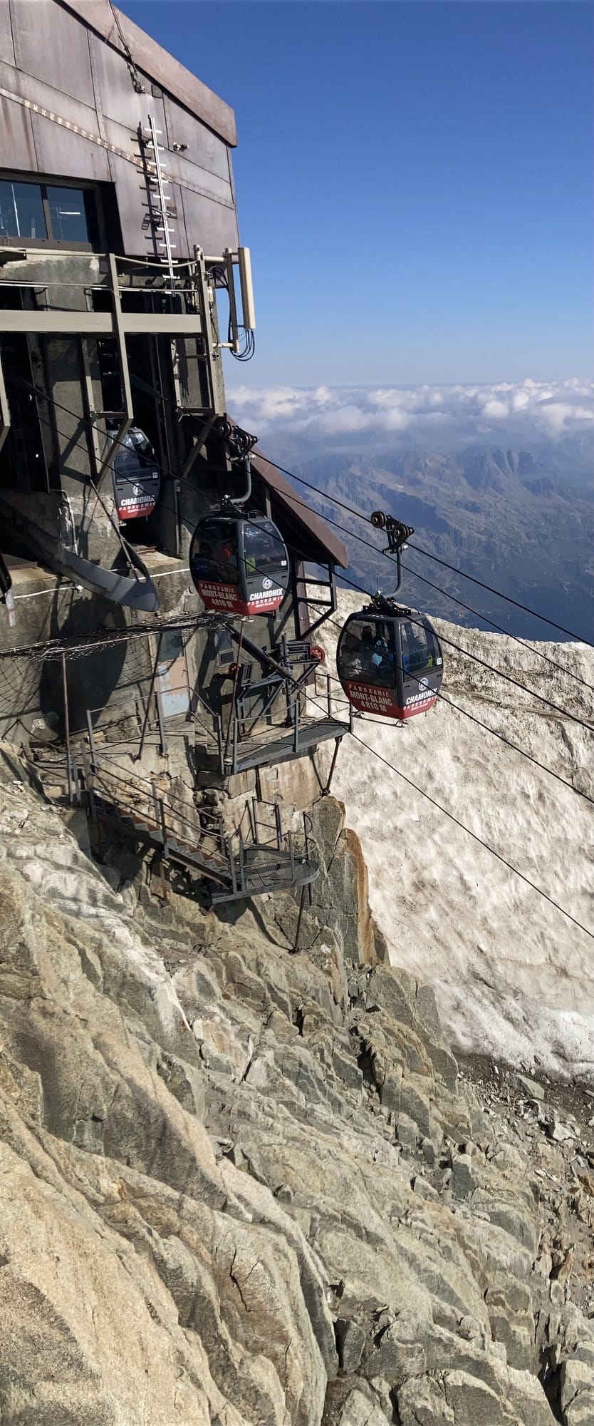 Cable cars of the Panoramic Mont-Blanc line suspended above rock and ice at the Aiguille du Midi upper station — Chamonix-Mont-Blanc, France