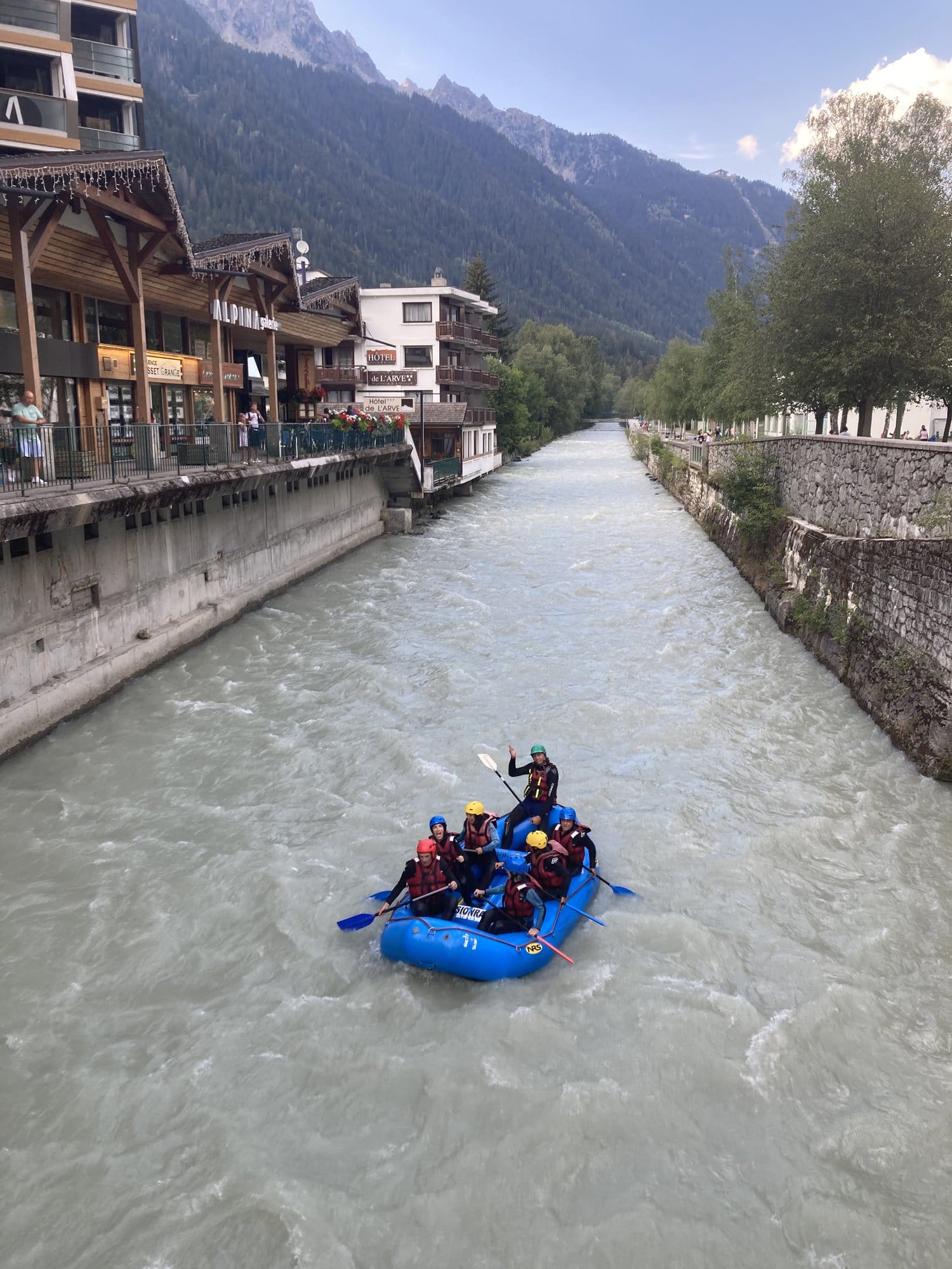 White-water rafting on the turquoise Arve river flowing through the centre of Chamonix, with alpine buildings on both banks — Chamonix-Mont-Blanc, France