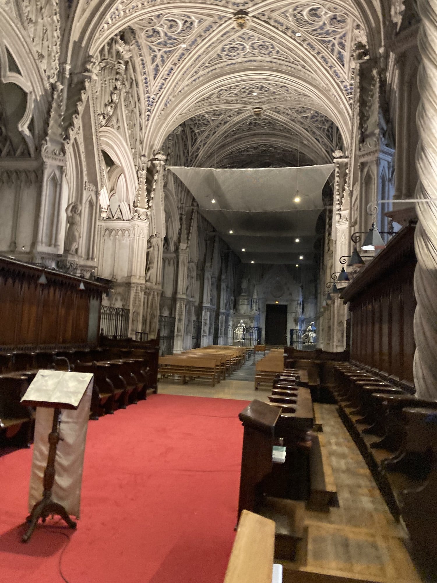 Interior of the Abbaye de Hautecombe showing elaborate Gothic vaulted ceilings, ornate choir stalls, and a red carpet running through the nave — Lac du Bourget, France