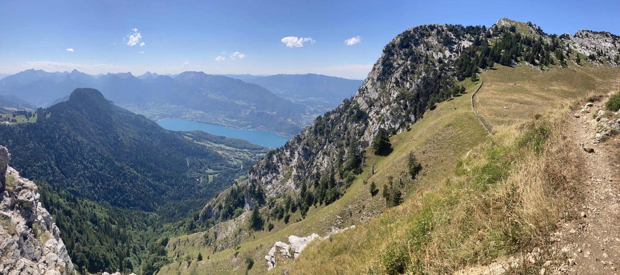 Panoramic view from a hiking trail at 1,650m overlooking the turquoise Lac d'Annecy, with limestone cliffs and mountains framing the lake — Lac d'Annecy, France