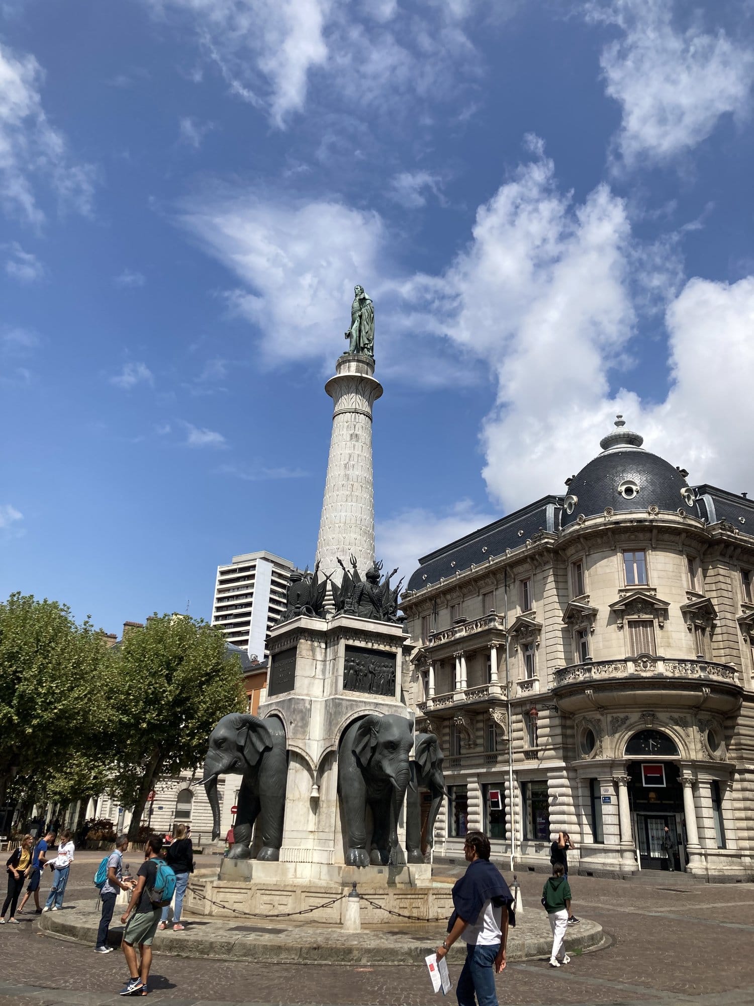 The Fontaine des Éléphants in Chambéry, with four bronze elephants supporting a tall column, flanked by elegant 19th-century buildings — Chambéry, France