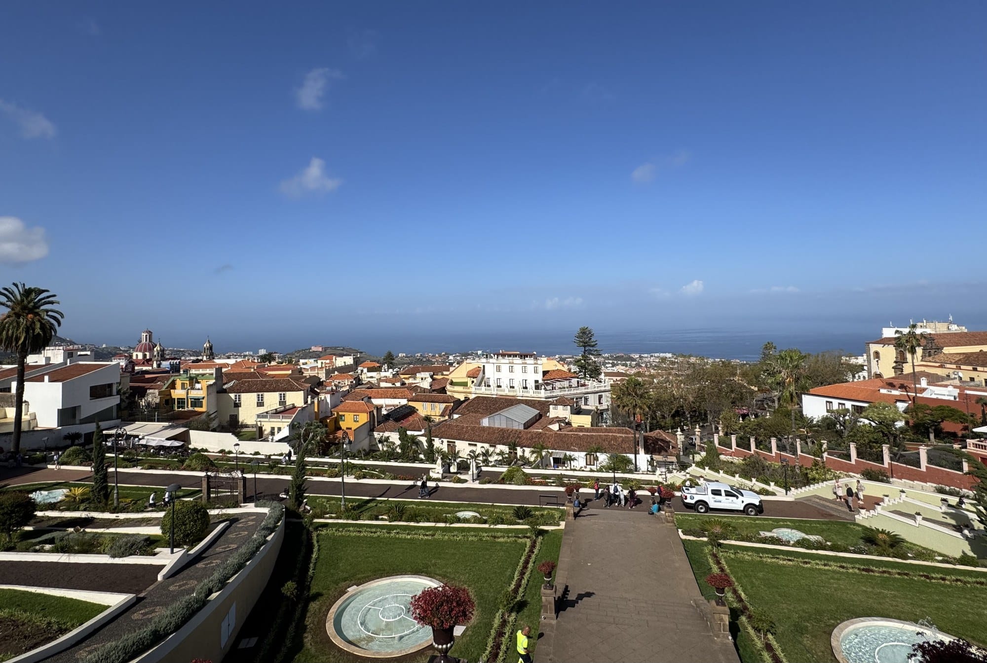 A panoramic view of La Orotava's historic centre: tiled red roofs stepping down a hillside toward the Atlantic Ocean — Tenerife