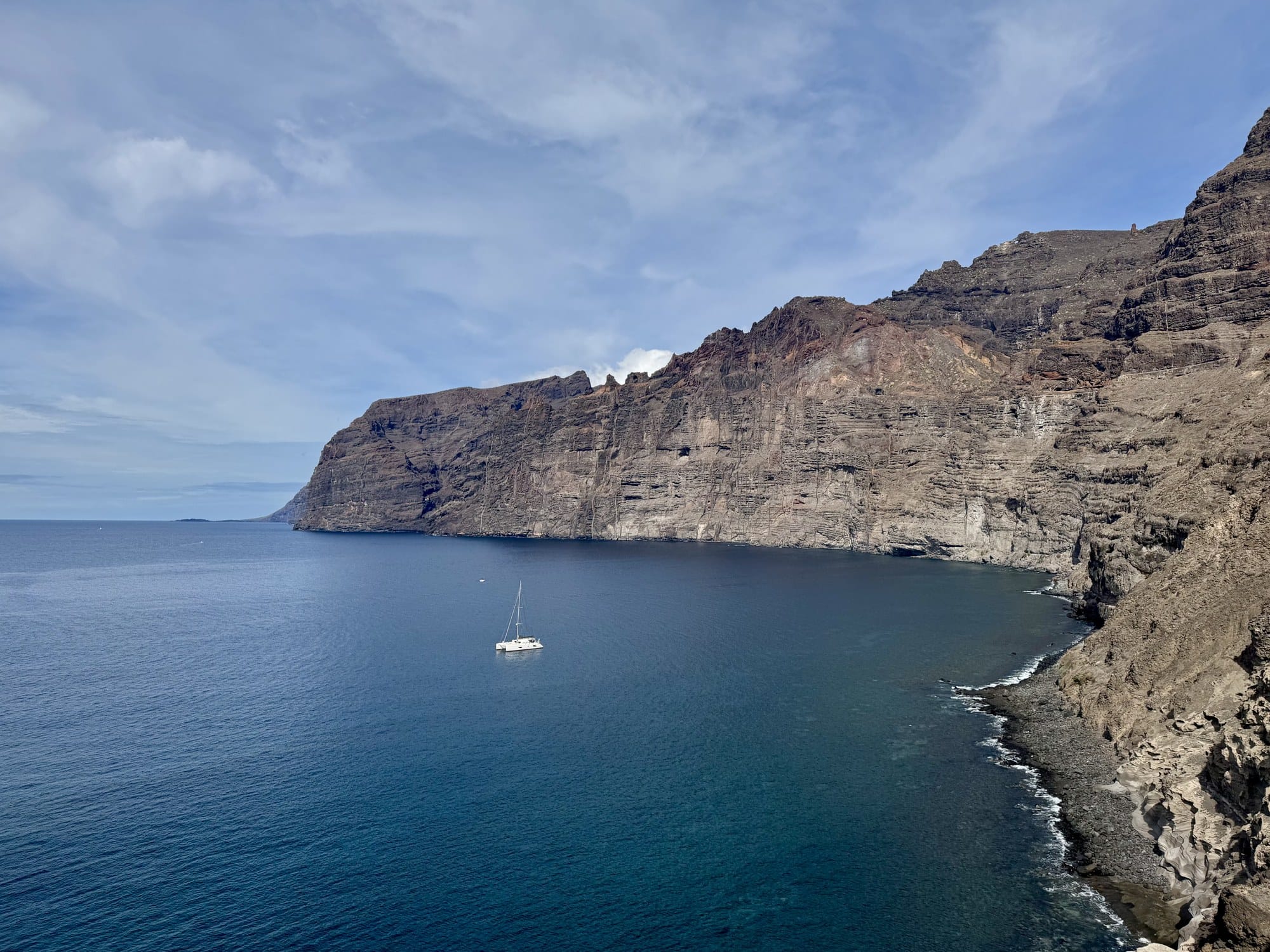 Un catamarano che naviga sotto le imponenti scogliere di Los Gigantes, la parete di basalto verticale alta 500 metri fuori dall'Atlantico — Tenerife