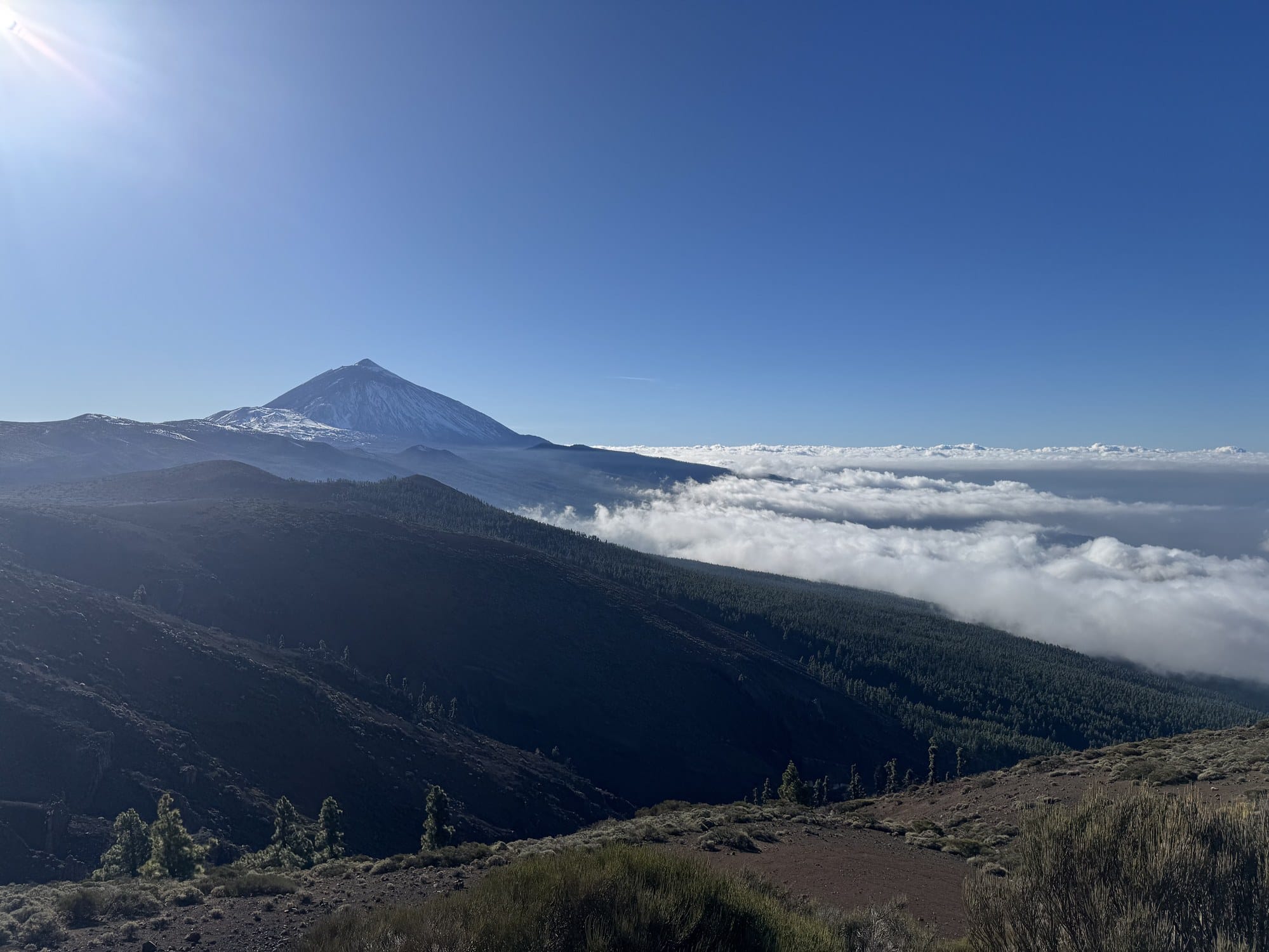 The perfect snow-capped cone of Teide rising above a thick sea of clouds, seen at sunset from Mirador de Chipeque — Tenerife