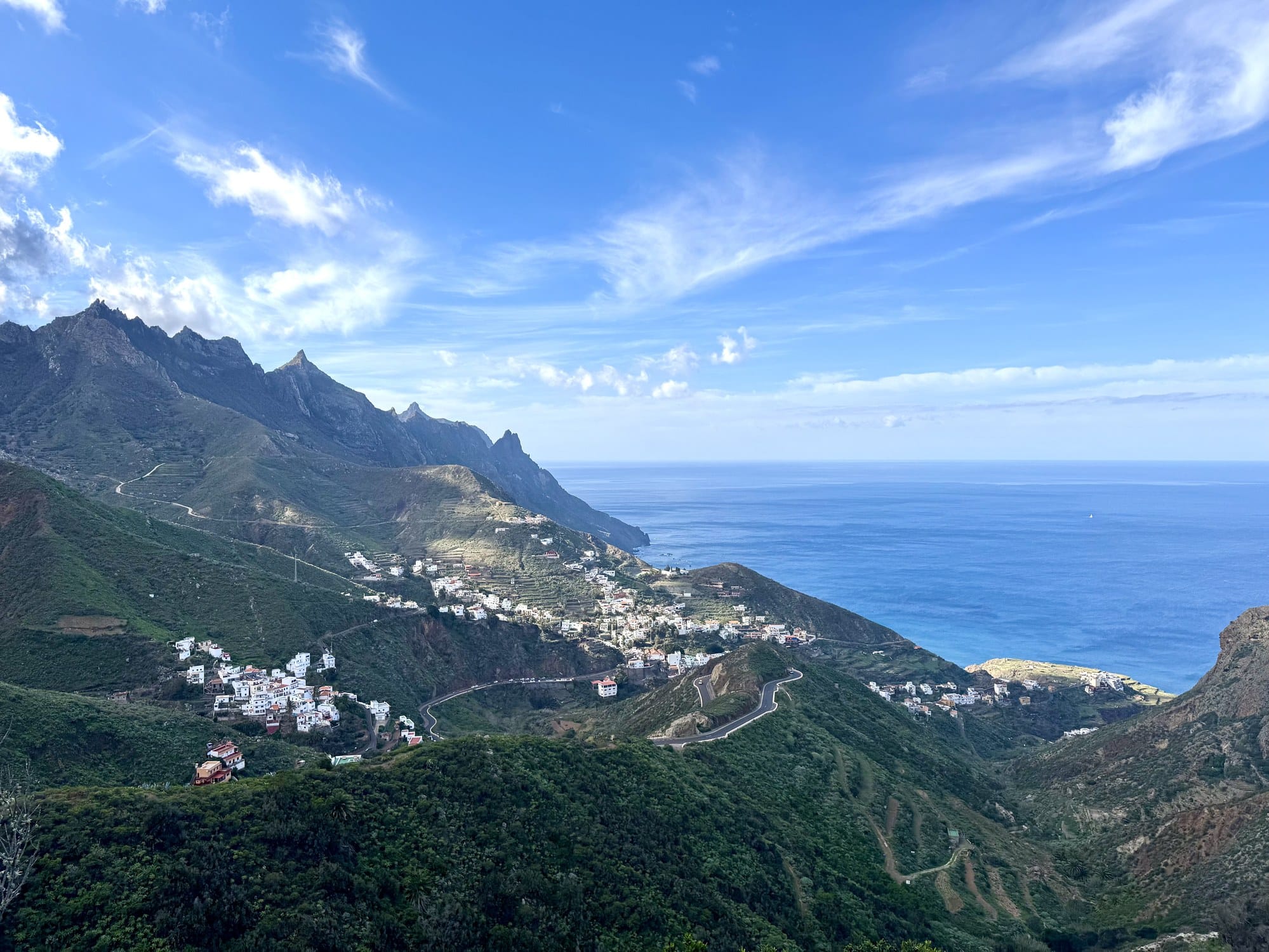 A stunning view of Taganana village spread along a narrow ridge in Anaga Rural Park, with jagged peaks behind and the Atlantic below — Tenerife