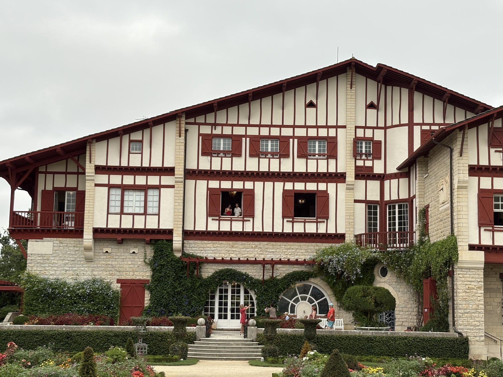 The facade of Villa Arnaga showing the distinctive neo-Basque architecture with red-and-white half-timbering and ivy-covered walls — Cambo-les-Bains, French Basque Country