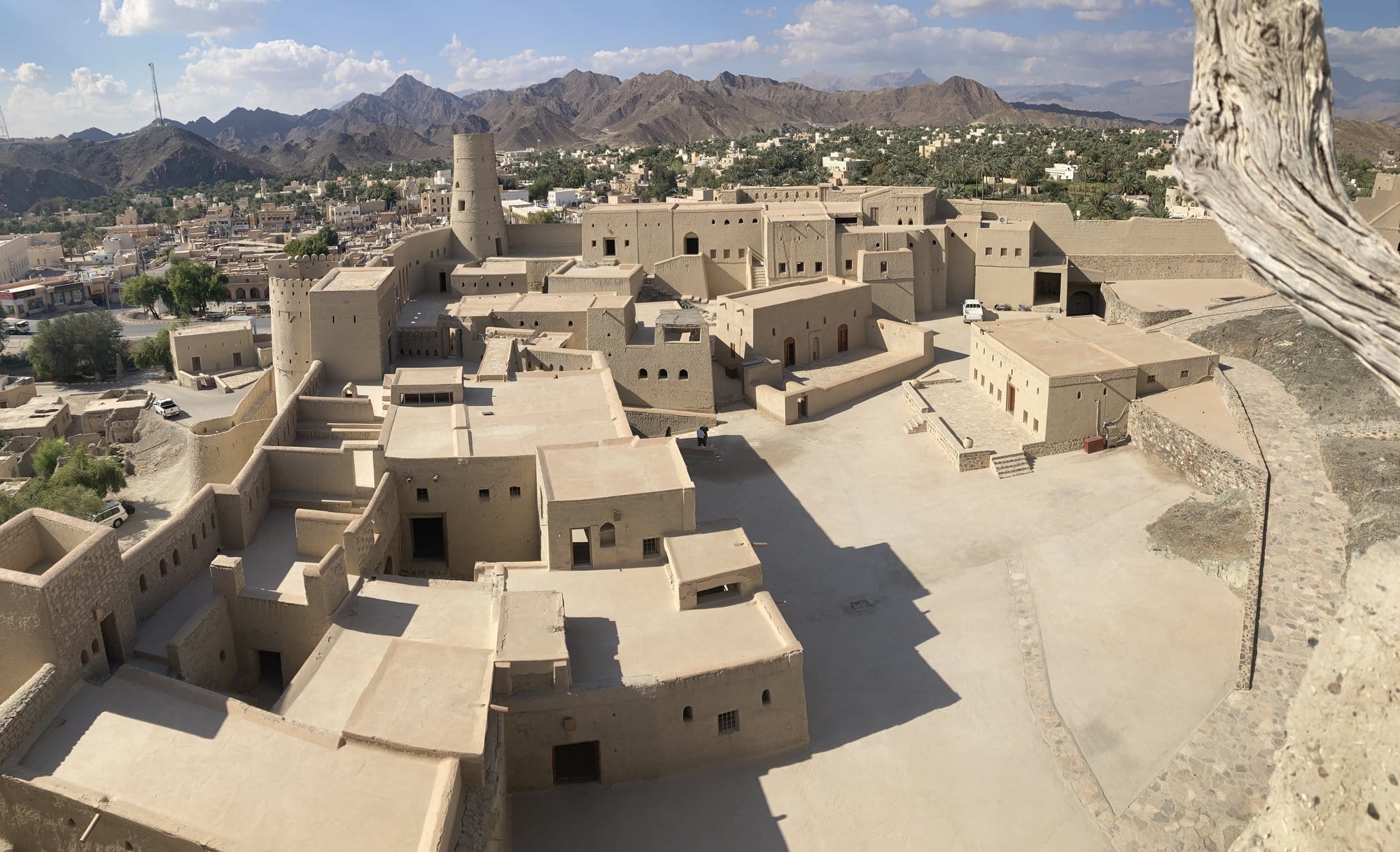 Panoramic view from the top of Bahla Fort showing the mud-brick buildings and town below — Bahlā', Oman