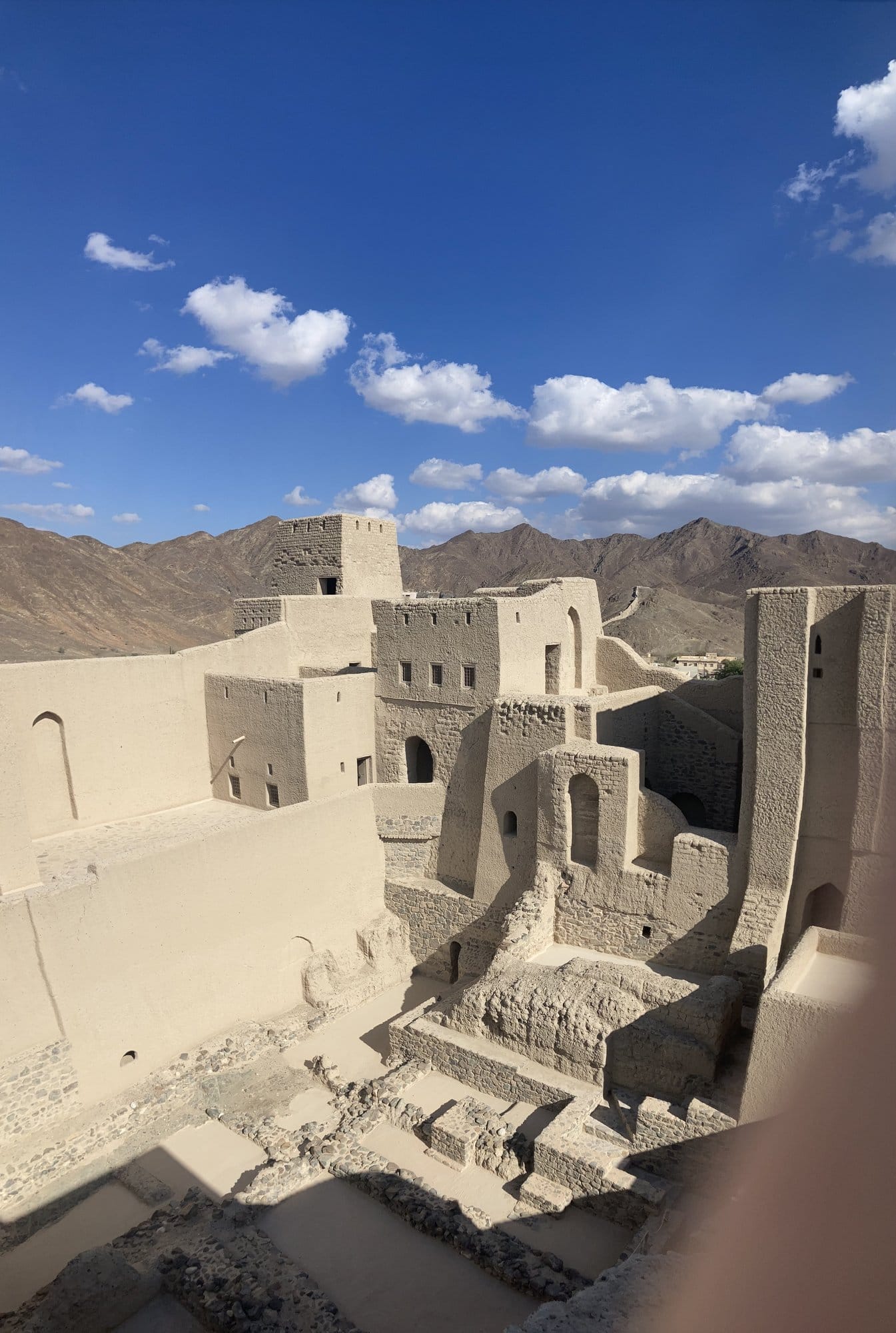The imposing walls and towers of Bahla Fort against a backdrop of arid mountains — Bahlā', Oman