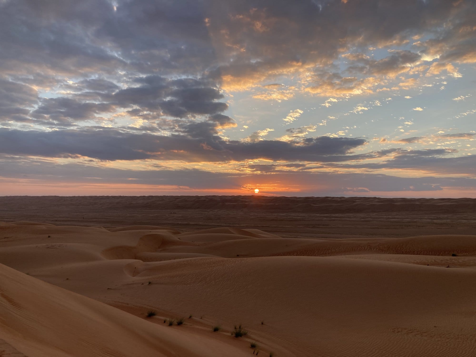 Sunset over the endless dunes of the Wahiba Sands with dramatic clouds — Badīyah, Oman
